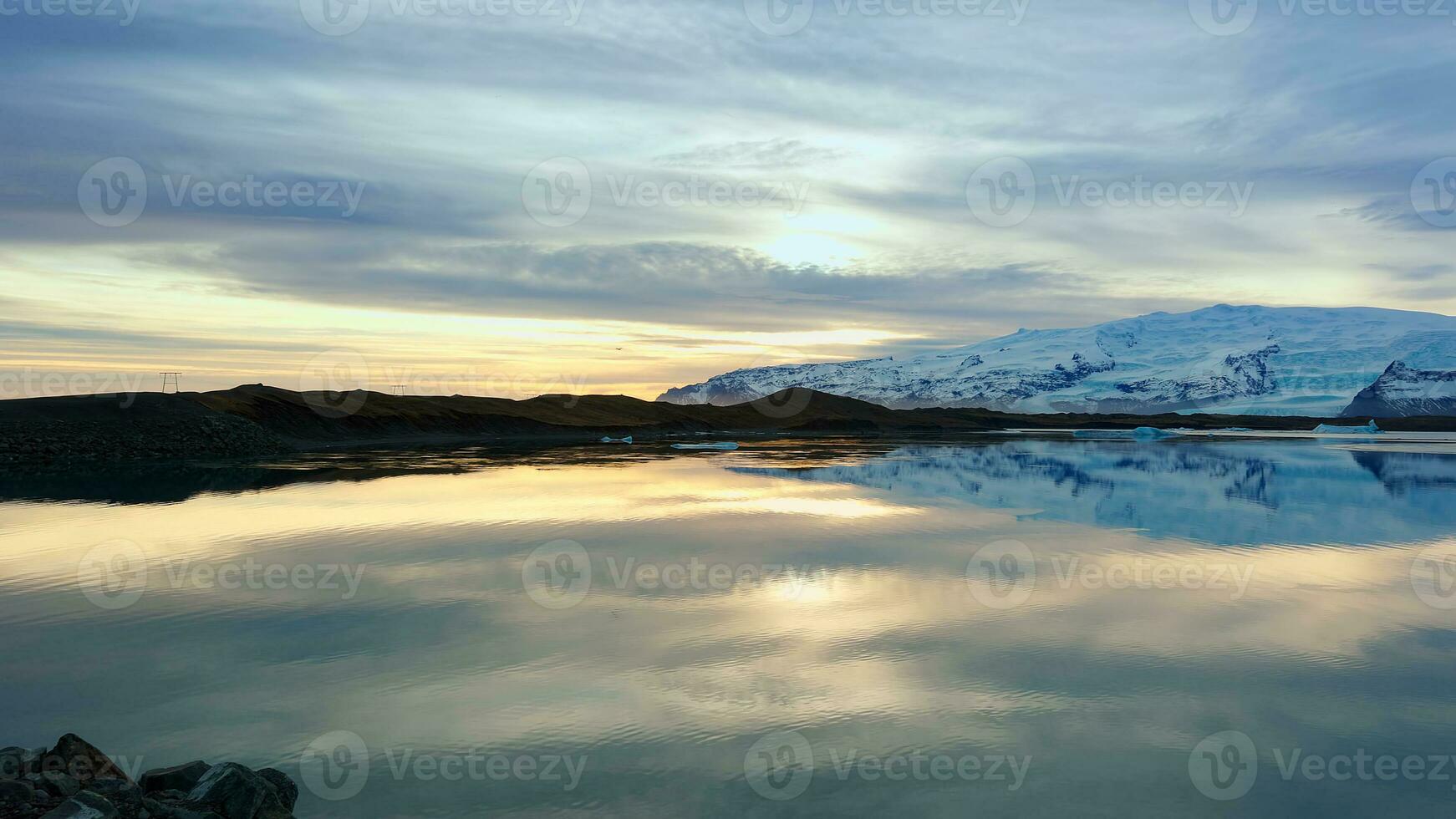 lago e nevoso montagne nel Islanda con bellissimo paesaggio, congelamento freddo acqua. scandinavo natura scenario con colline e campi, panoramico Visualizza panoramico percorso. palmare sparo. foto