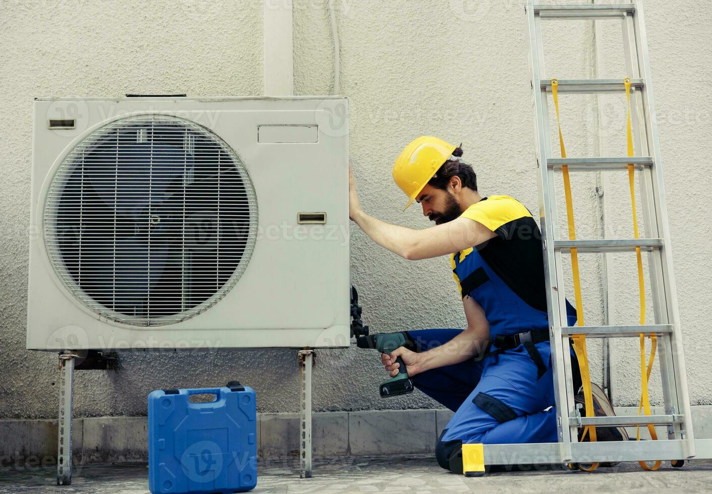 competente riparatore di partenza opera su difettoso aria condizionatore, utilizzando palmare trapano per smontare condensatore metallo bobina pannello. preciso meccanico smantellamento HVAC sistema per dai un'occhiata per sporco foto