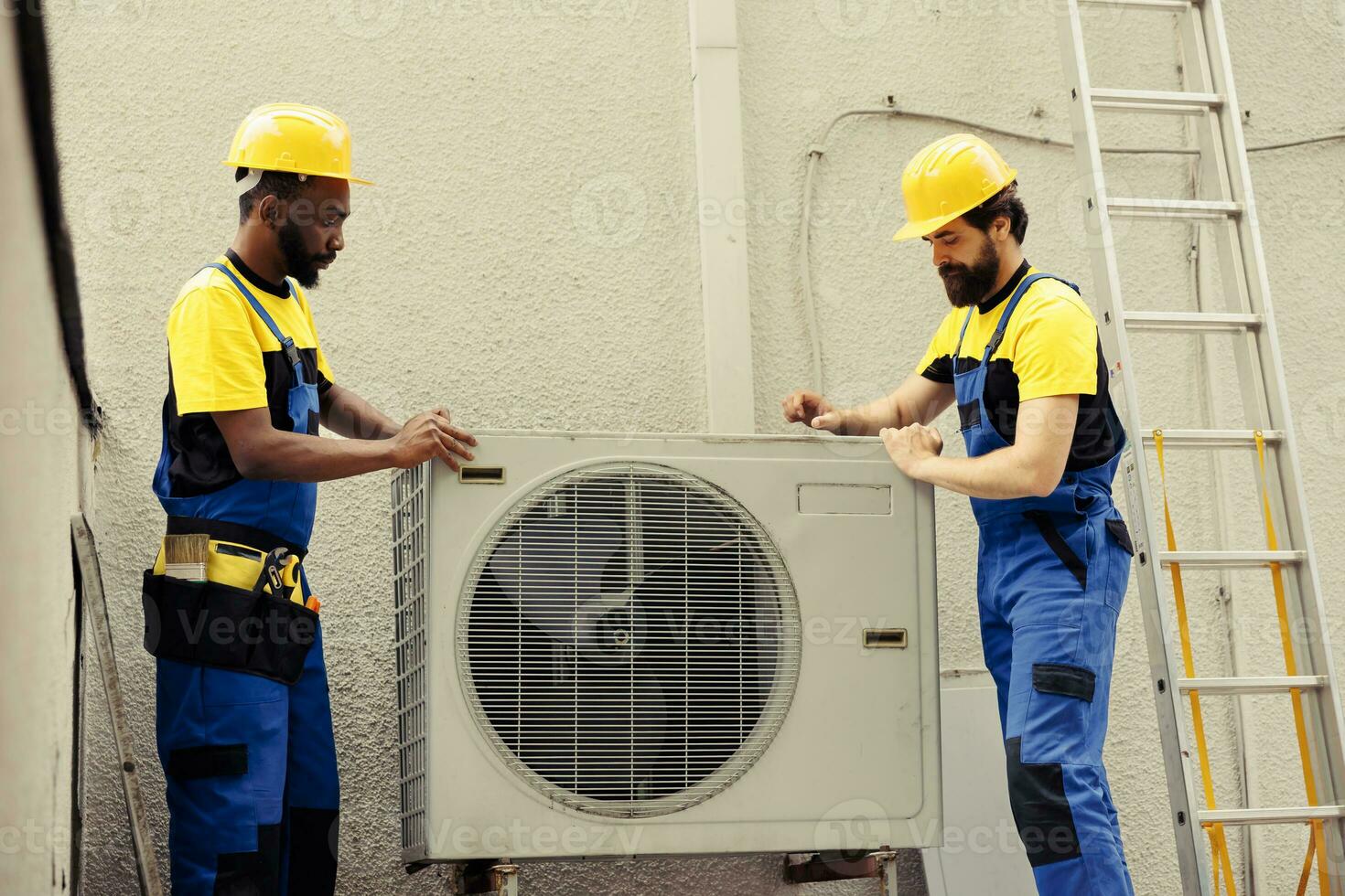 lavoro di gruppo certificato tecnici di partenza opera su rotto HVAC sistema, assunzione a parte condensatore bobina pannello. esperto wiremen smontaggio aria condizionatore per dai un'occhiata per cattivo cablaggio foto