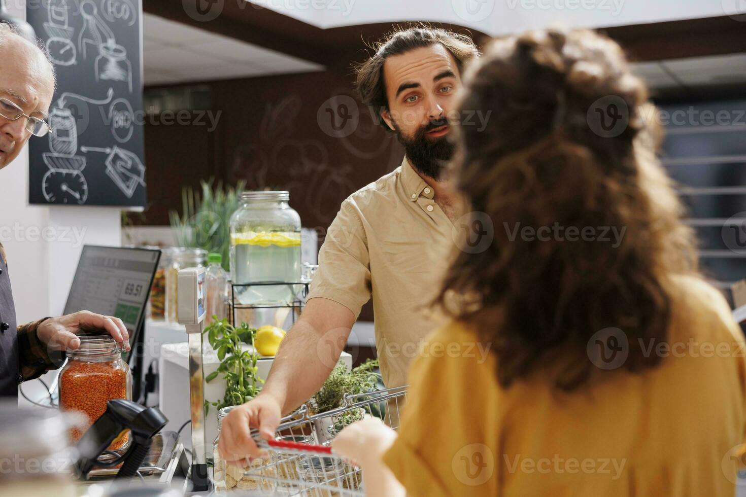 verde vivente coppia a zero rifiuto supermercato check-out contatore con shopping cestino pieno di biologico cibo. vegano i clienti in attesa per loro dispensa graffette per essere ponderato nel Locale Quartiere negozio foto