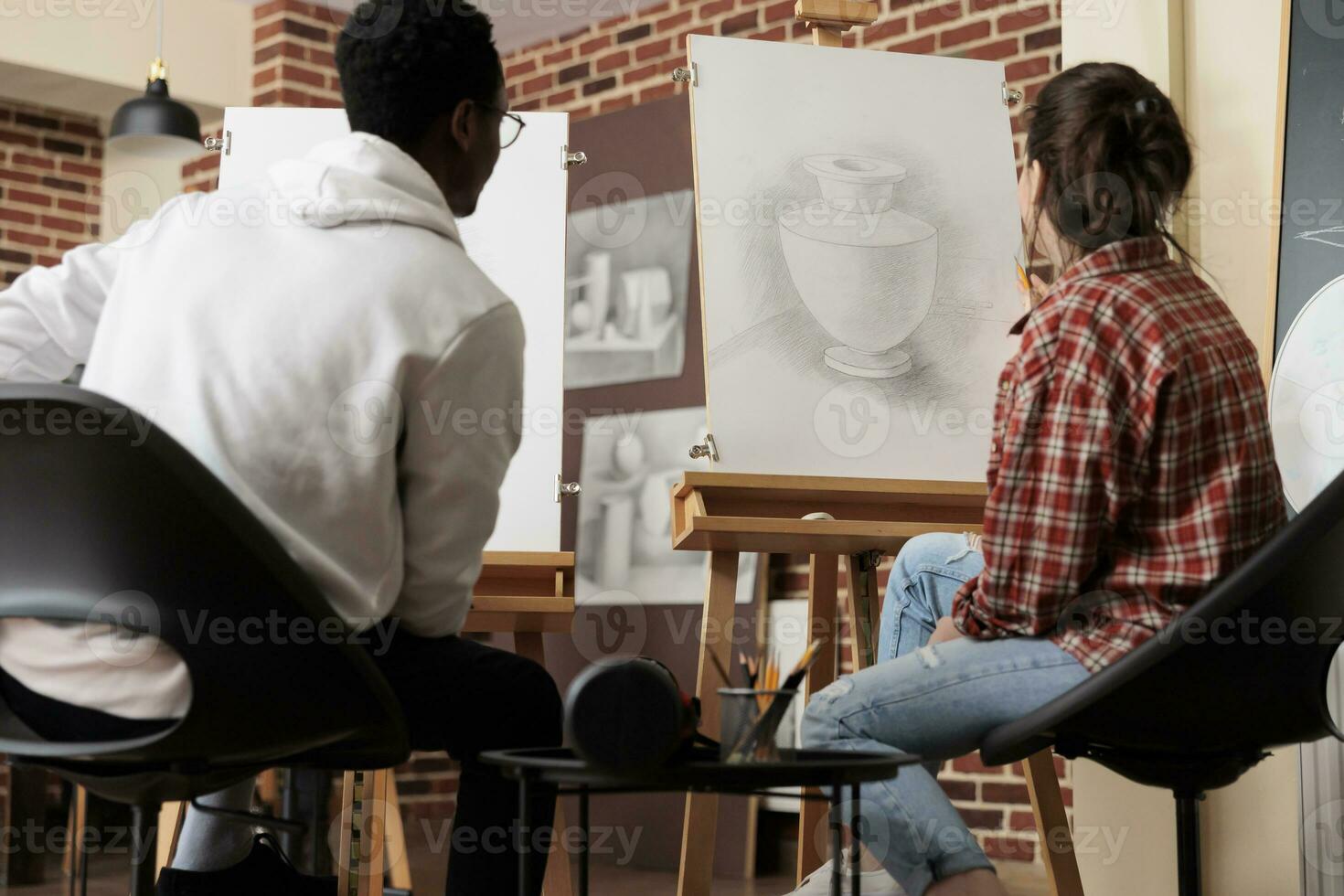 giovane diverso persone studenti guardare a tela con vaso schizzo, sviluppare abilità nel linea e forma mentre studiando nel arte accademia. multirazziale coppia seduta a cavalletti apprendimento per disegnare insieme foto