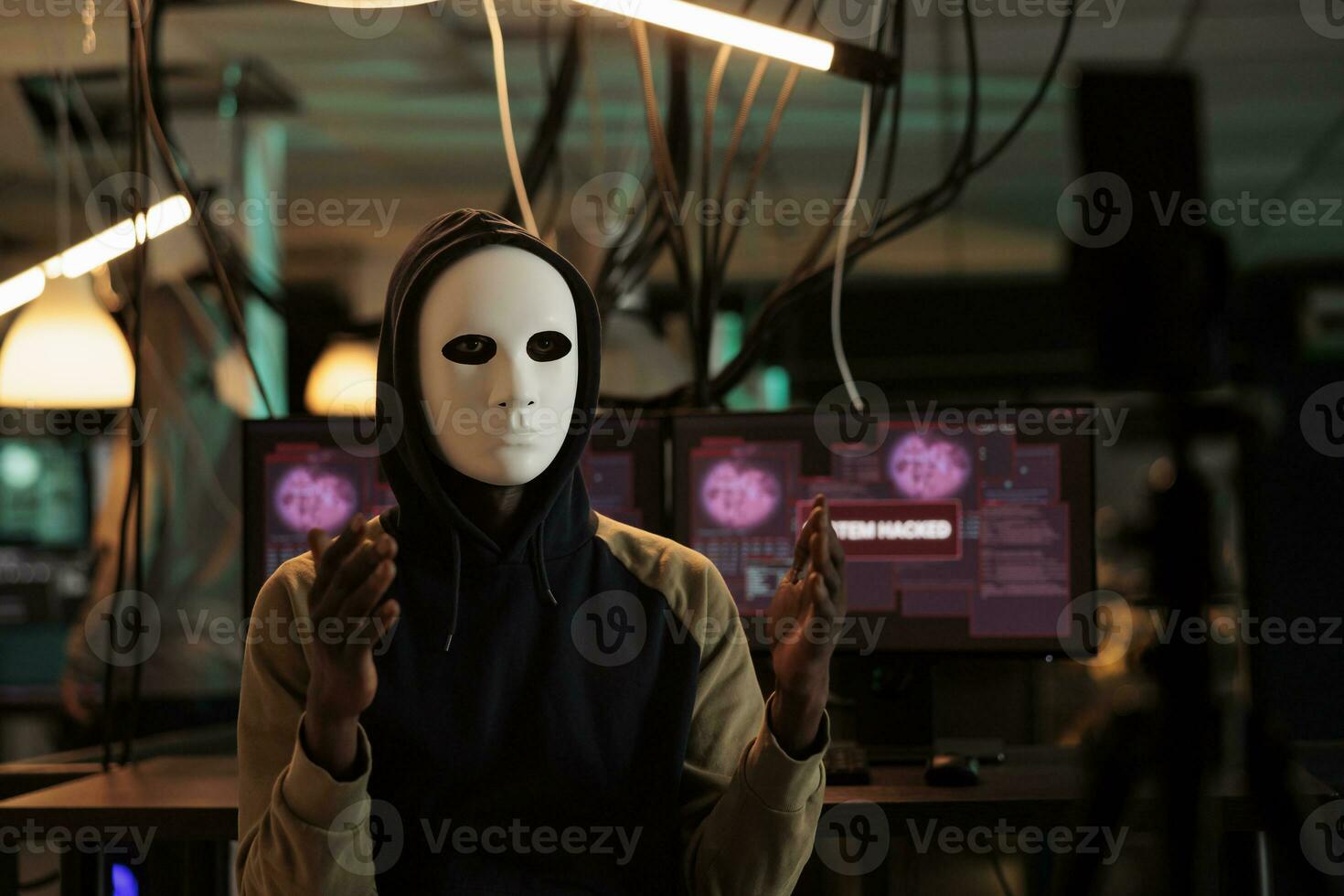 africano americano pirata emittente minaccia video a notte, indossare anonimo maschera e chiede ransomware. maschio spiare furto Banca dati informazione con trojan virus e computer malware. foto