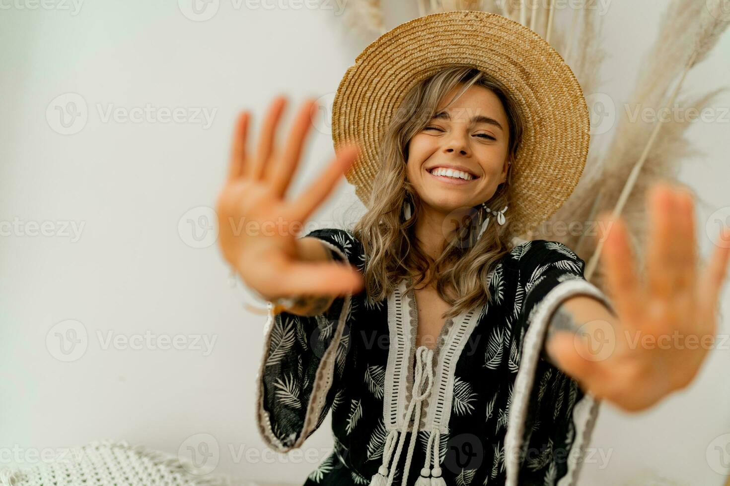 giocoso allegro donna nel cannuccia cappello Tirare mani per il telecamera. bianca sfondo. boho vestito. elegante estate accsesorises. foto