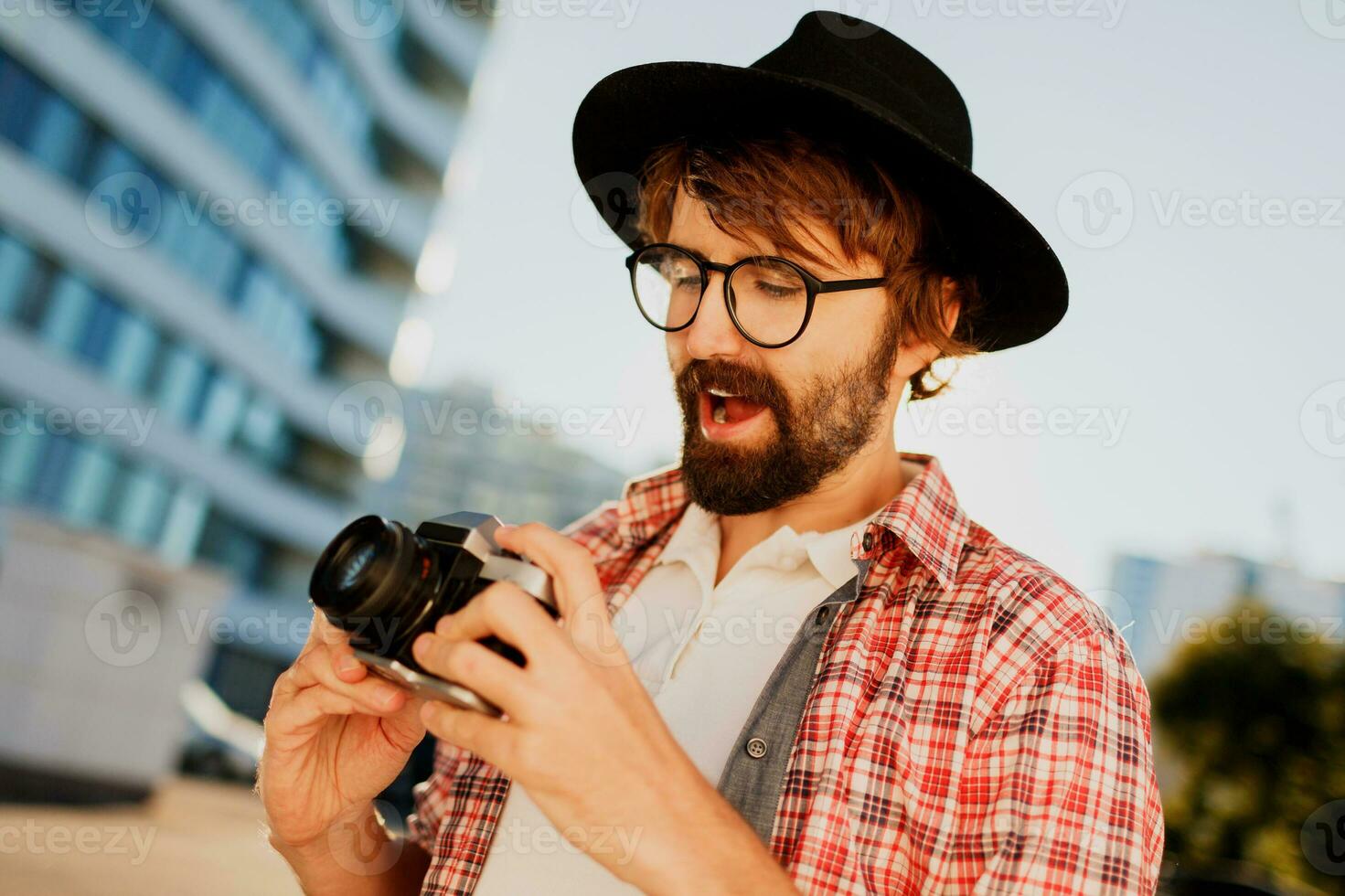 Uscito uomo con barba con interessante utilizzando retrò film telecamera , fabbricazione fotografie. turista criniera a piedi nel grande moderno città. foto