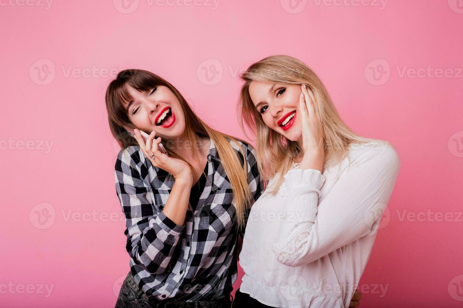 brunetta donna con sorpresa viso parlando di mobile Telefono. sua migliore amico ridendo e avendo divertimento. rosa sfondo. studio sparo. foto