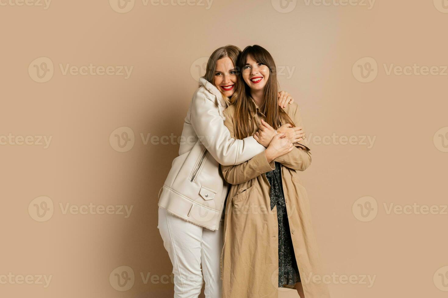 Due elegante donne nel elegante inverno attrezzatura in posa al di sopra di beige sfondo. indossare cappotto e giacca. shopping e moda concetto. foto