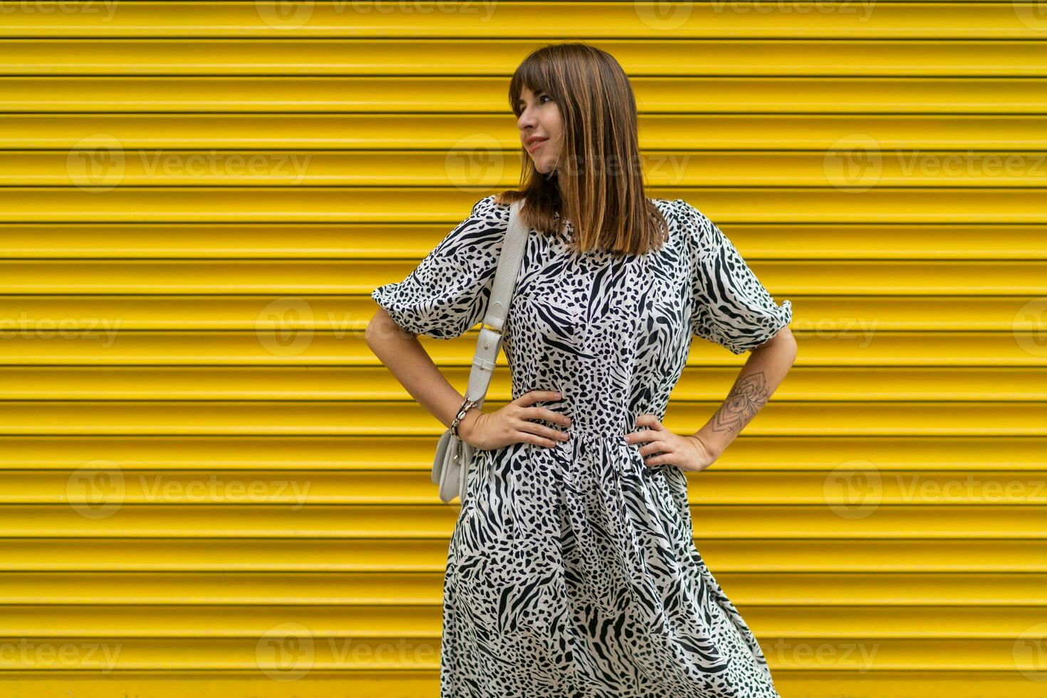 grazioso donna con tatoo su mano in posa al di sopra di giallo urbano parete. foto