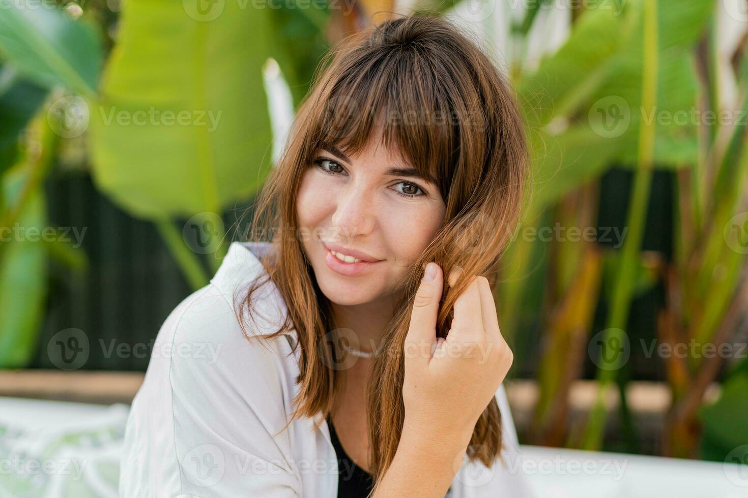 vicino su ritratto di sorridente europeo femmina in posa al di sopra di tropicale giardino su sfondo. foto