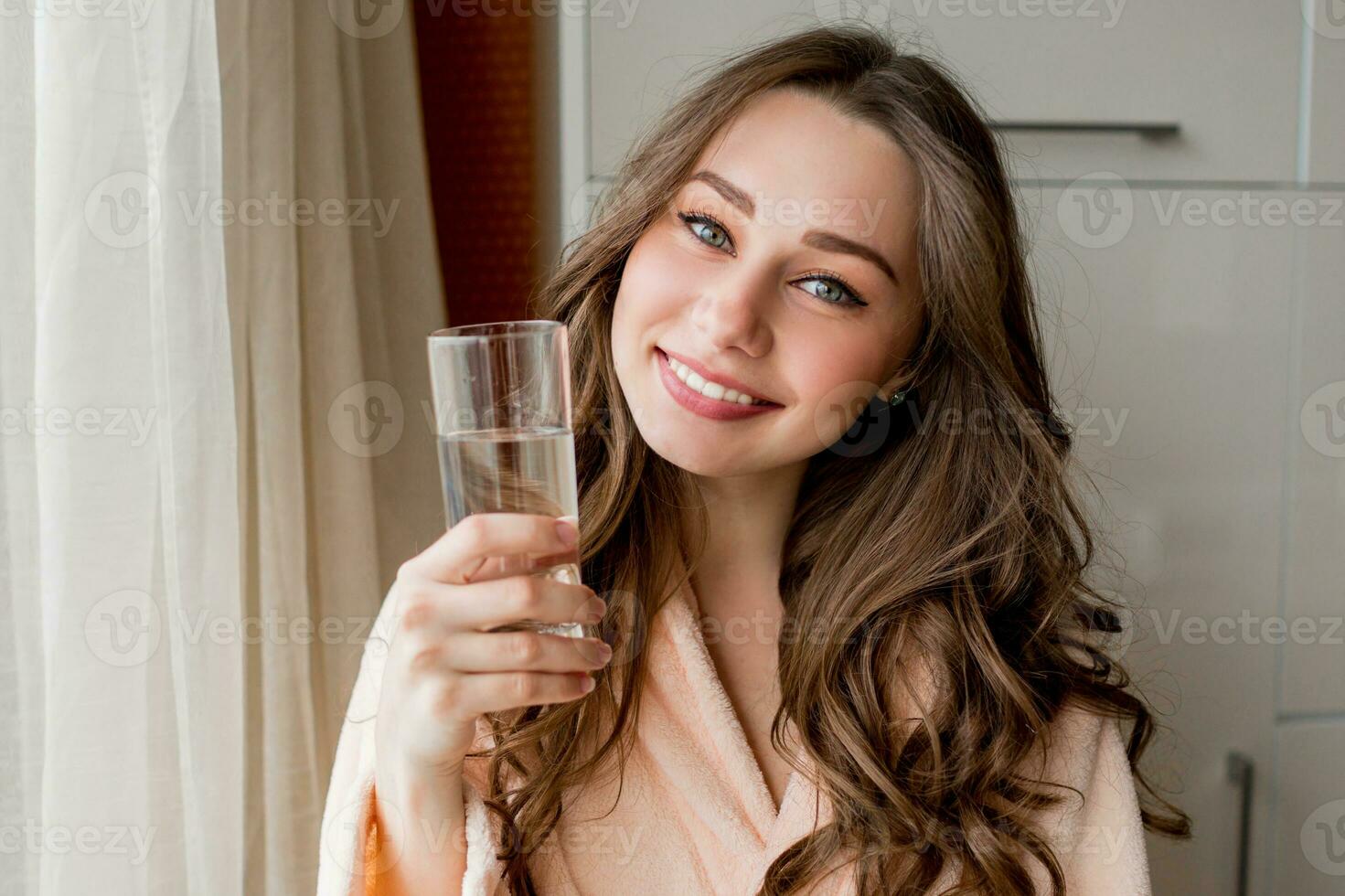 bella contento donna nel accappatoio potabile fresco acqua a casa . foto