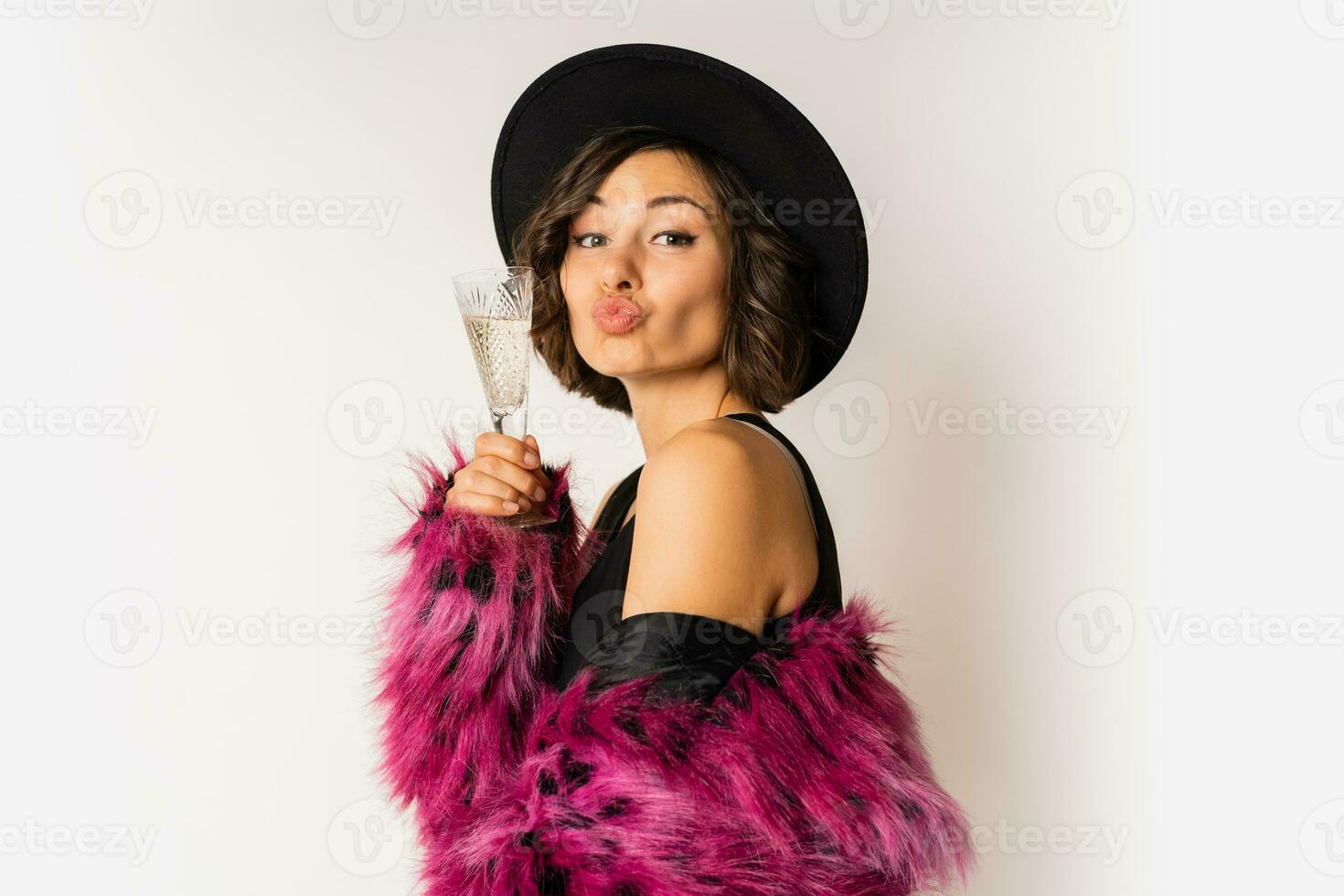 contento selezione donna nel elegante pelliccia cappotto Tenere bicchiere di shampoo , indossare rosa pelliccia cappotto e nero festa vestire. in posa al di sopra di bianca sfondo. foto