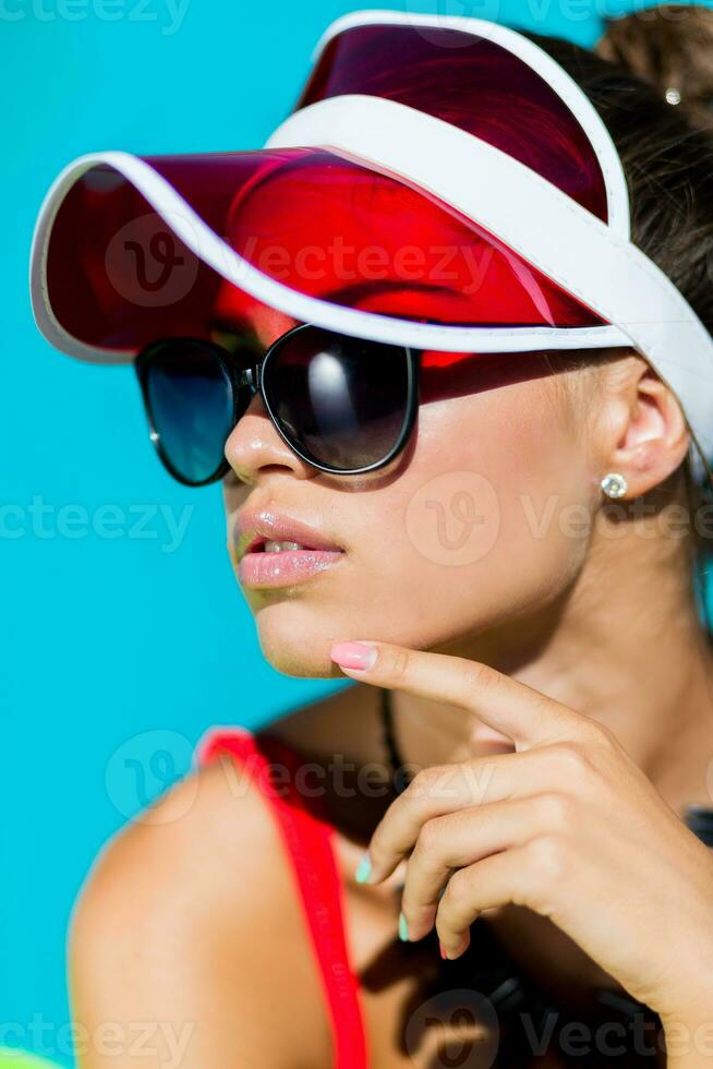sexy abbronzato donna nel rosso costume da bagno avendo divertimento e godendo estate nel sorprendente grande nuoto piscina. elegante trasparente cap. spiaggia festa. foto