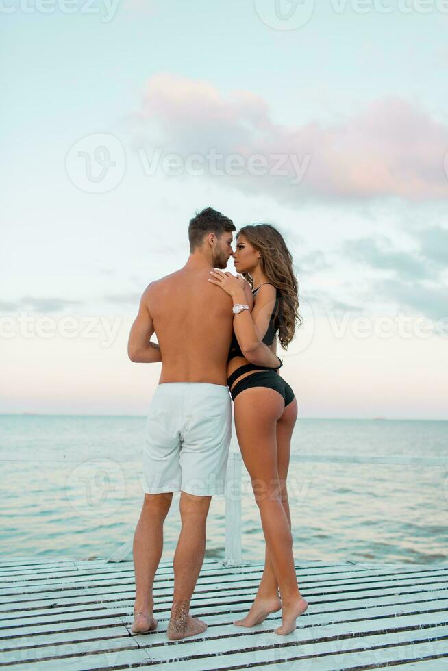 all'aperto moda ritratto di bella sexy coppia nel amore abbracci su sorprendente tropicale spiaggia, indossare elegante costumi da bagno. foto