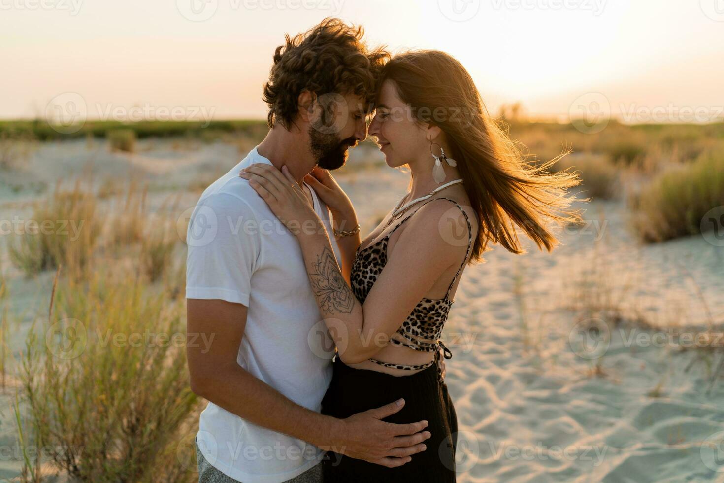 bellissimo coppia nel amore in posa su tropicale spiaggia. bello uomo con barba abbracciare il suo fidanzata. tropicale boho vestito. foto