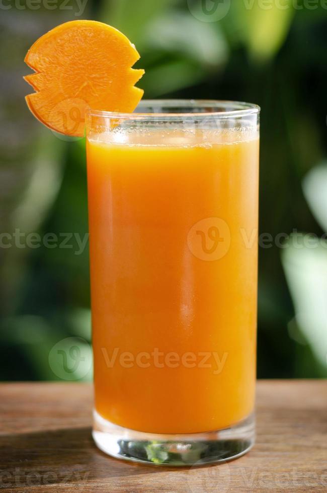 bicchiere di succo di carota fresco biologico sul tavolo all'aperto sul tavolo in giardino soleggiato all'aperto foto