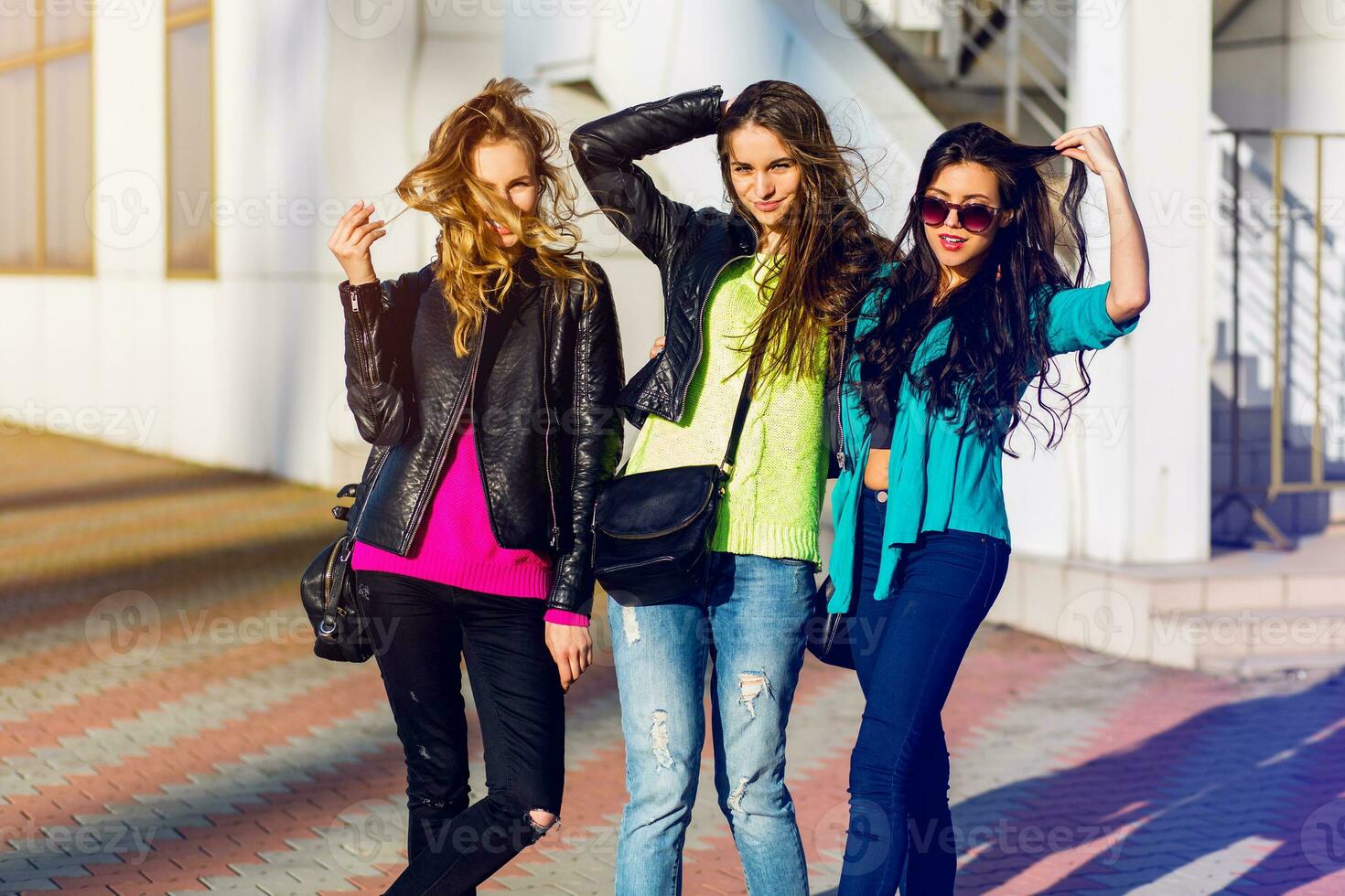 tre migliore amici avere divertimento su soleggiato autunno giorno urbano strada sfondo . gruppo di studenti a passeggio, indossare colore autunno maglione e pelle giacca. luminosa colori. foto