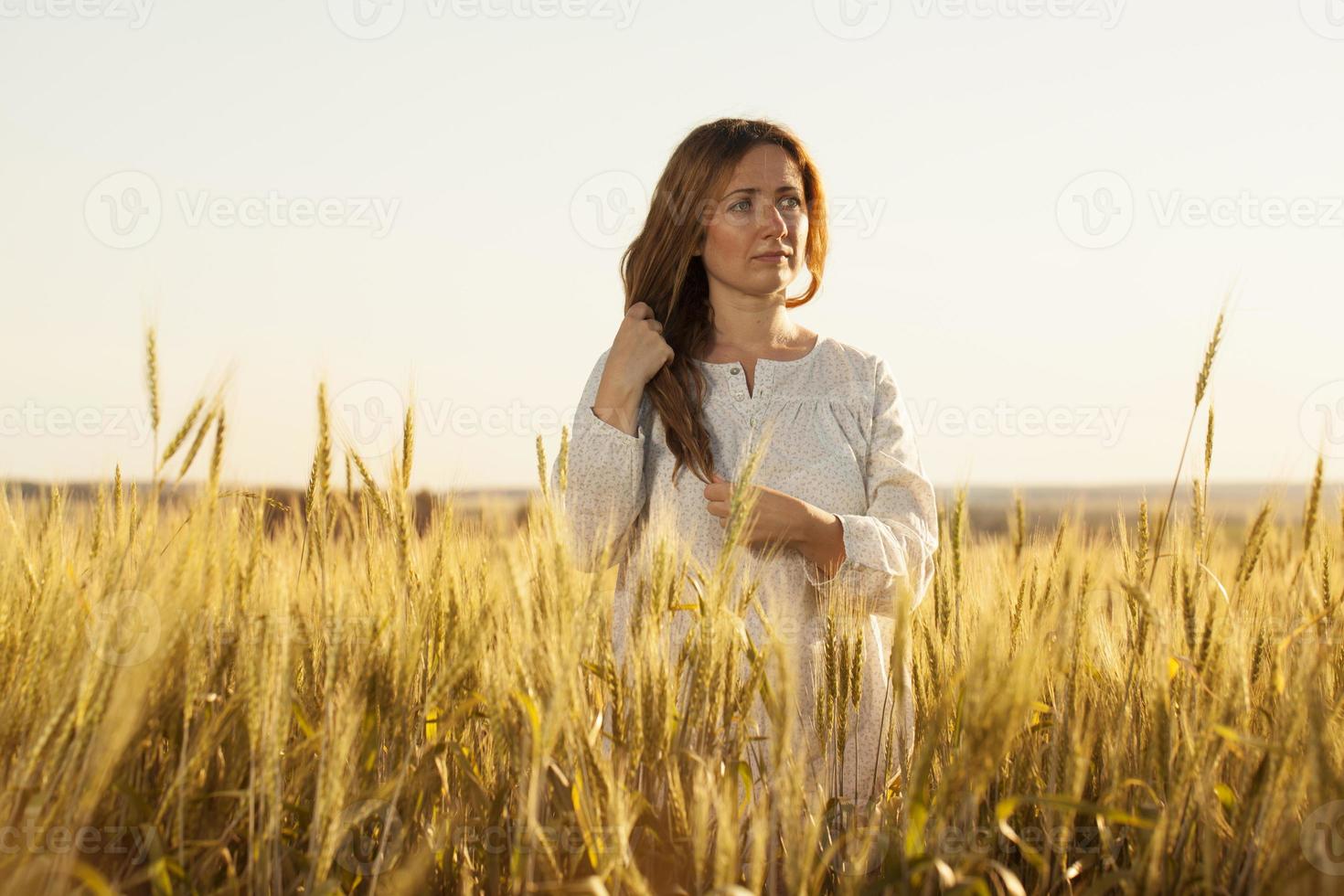 giovane donna sta in mezzo a un campo di grano foto