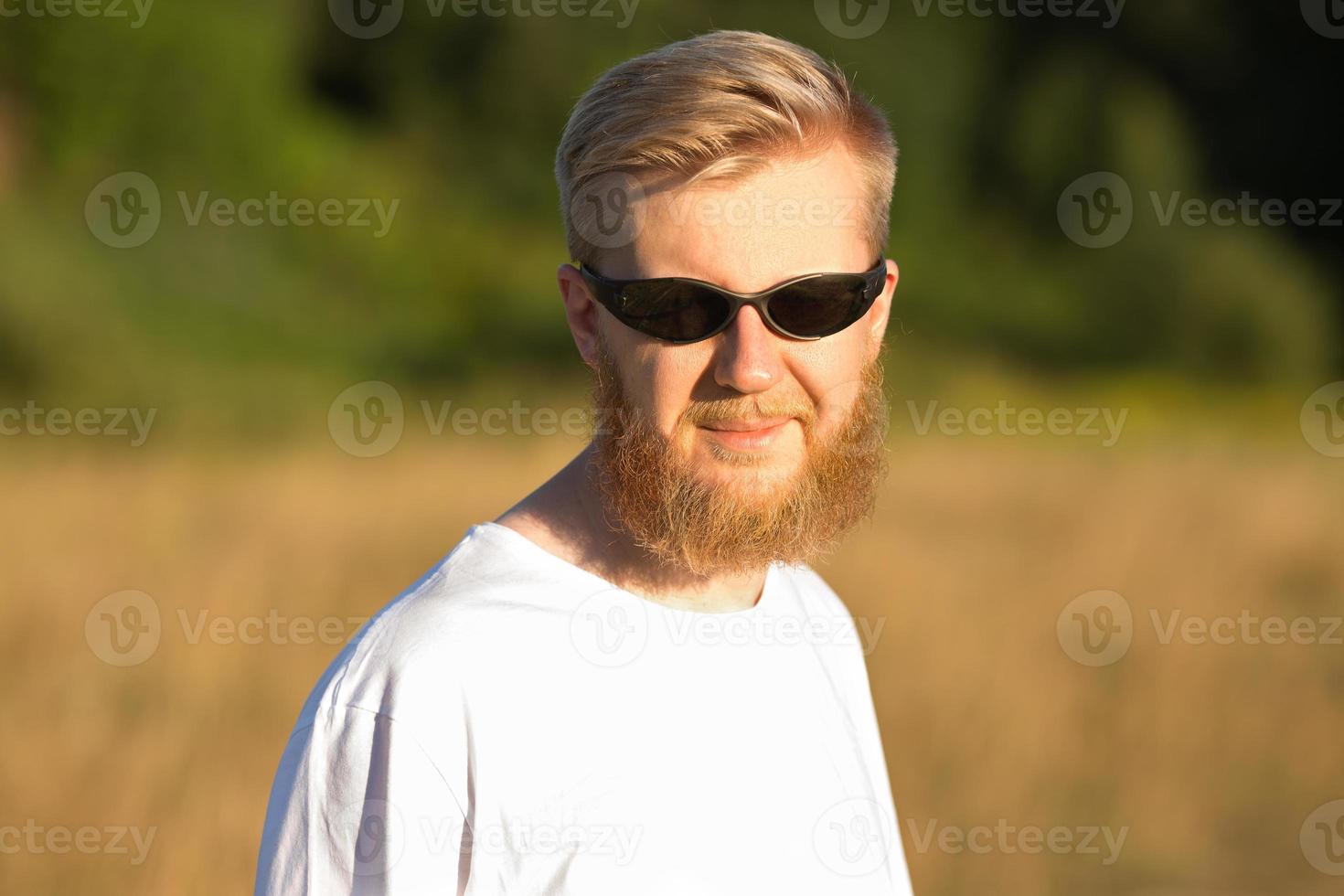 giovane uomo barbuto sorridente in occhiali da sole foto