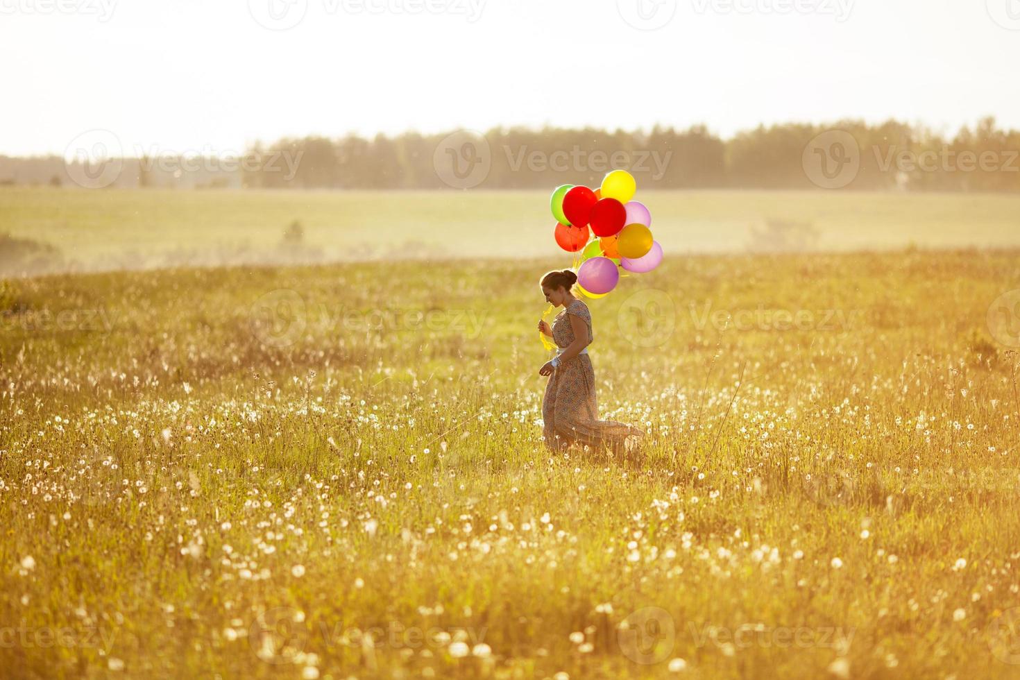 giovane donna felice con palloncini in un campo foto