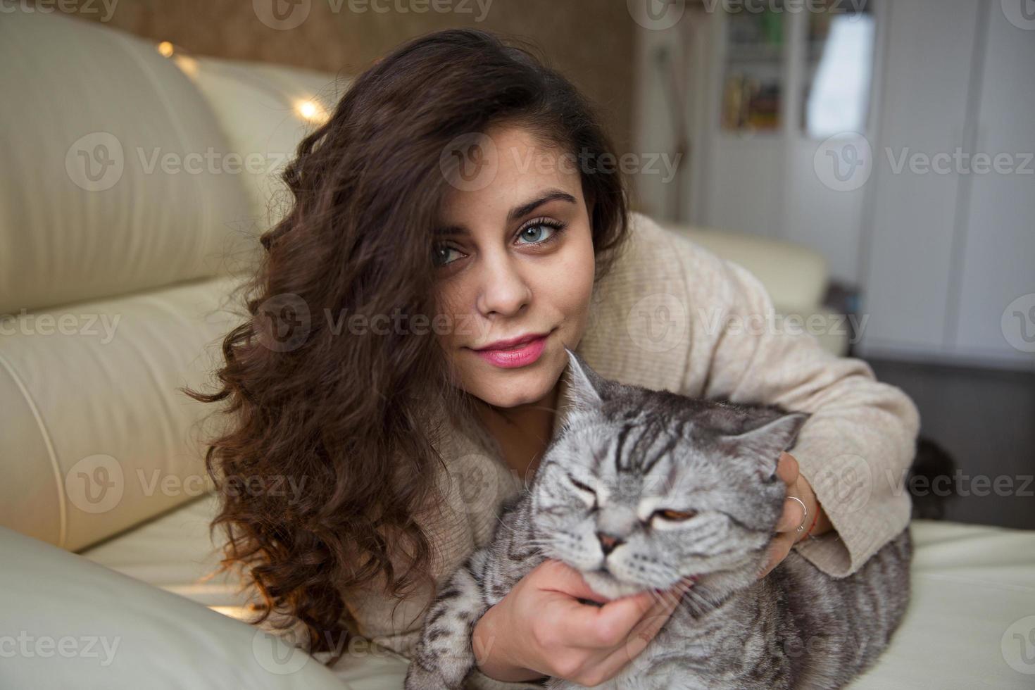 giovane donna che accarezza un gatto grigio foto