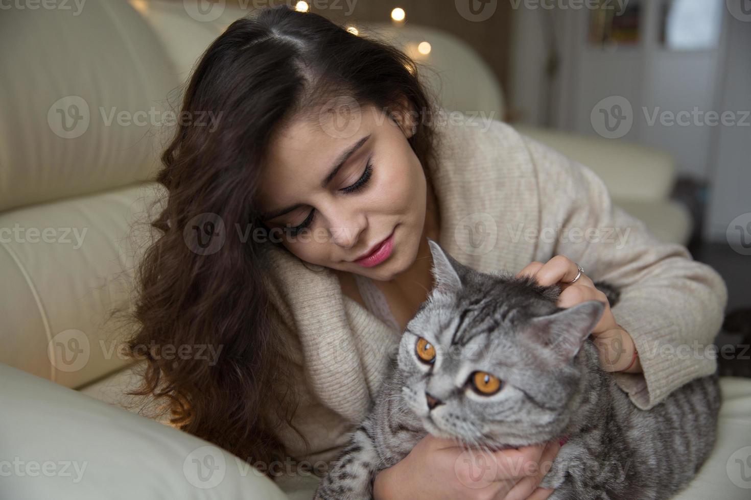 bella ragazza è sdraiata accanto a un gatto foto