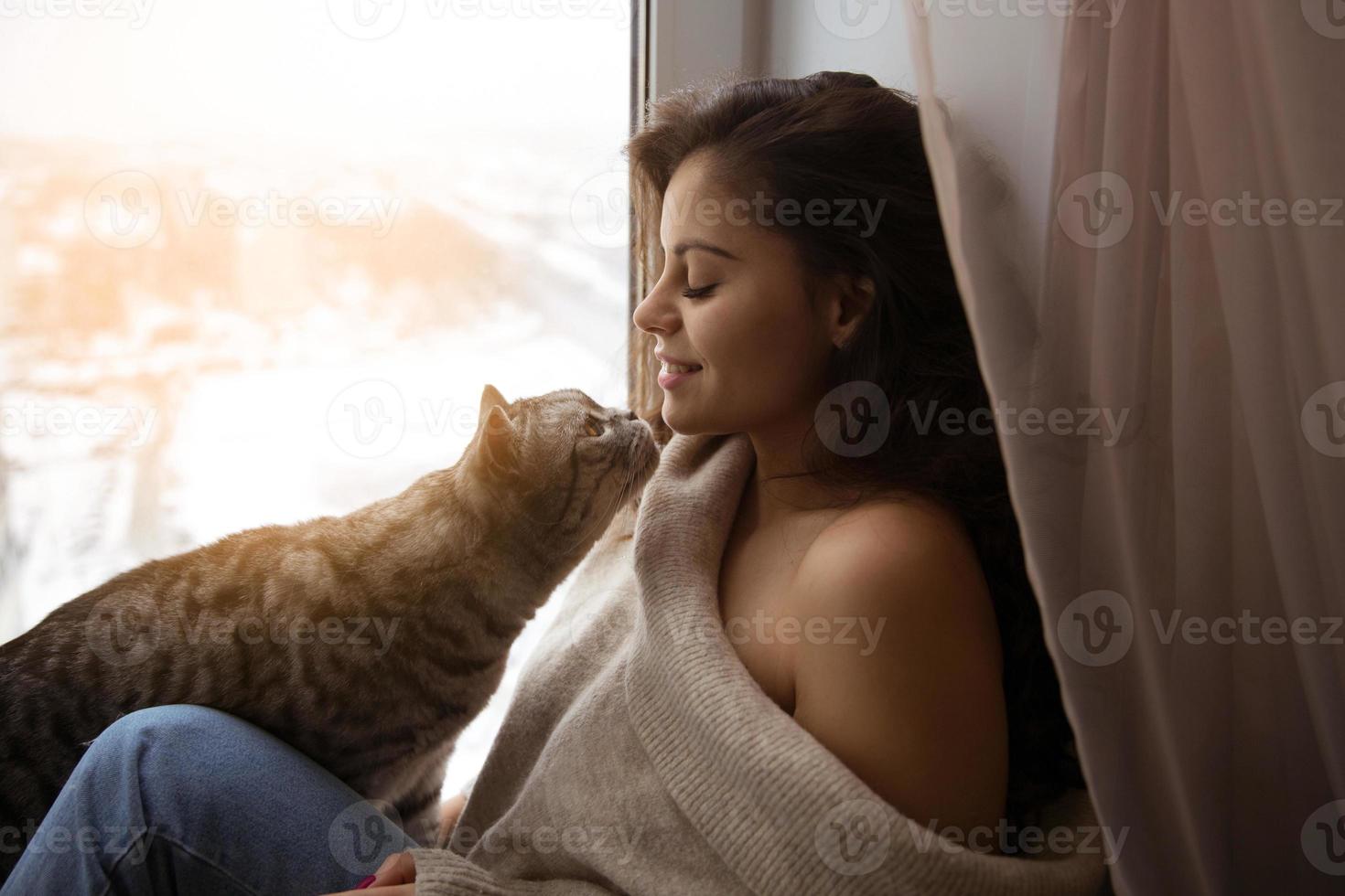 ragazza e un grosso gatto vicino alla finestra foto