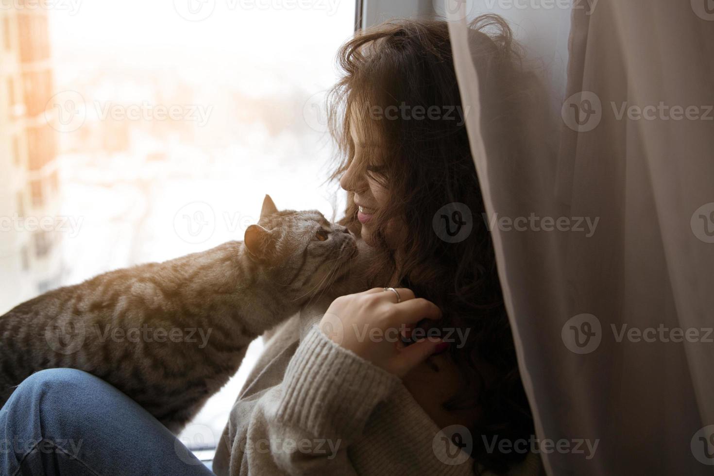 la ragazza si siede e si accarezza con un gatto foto
