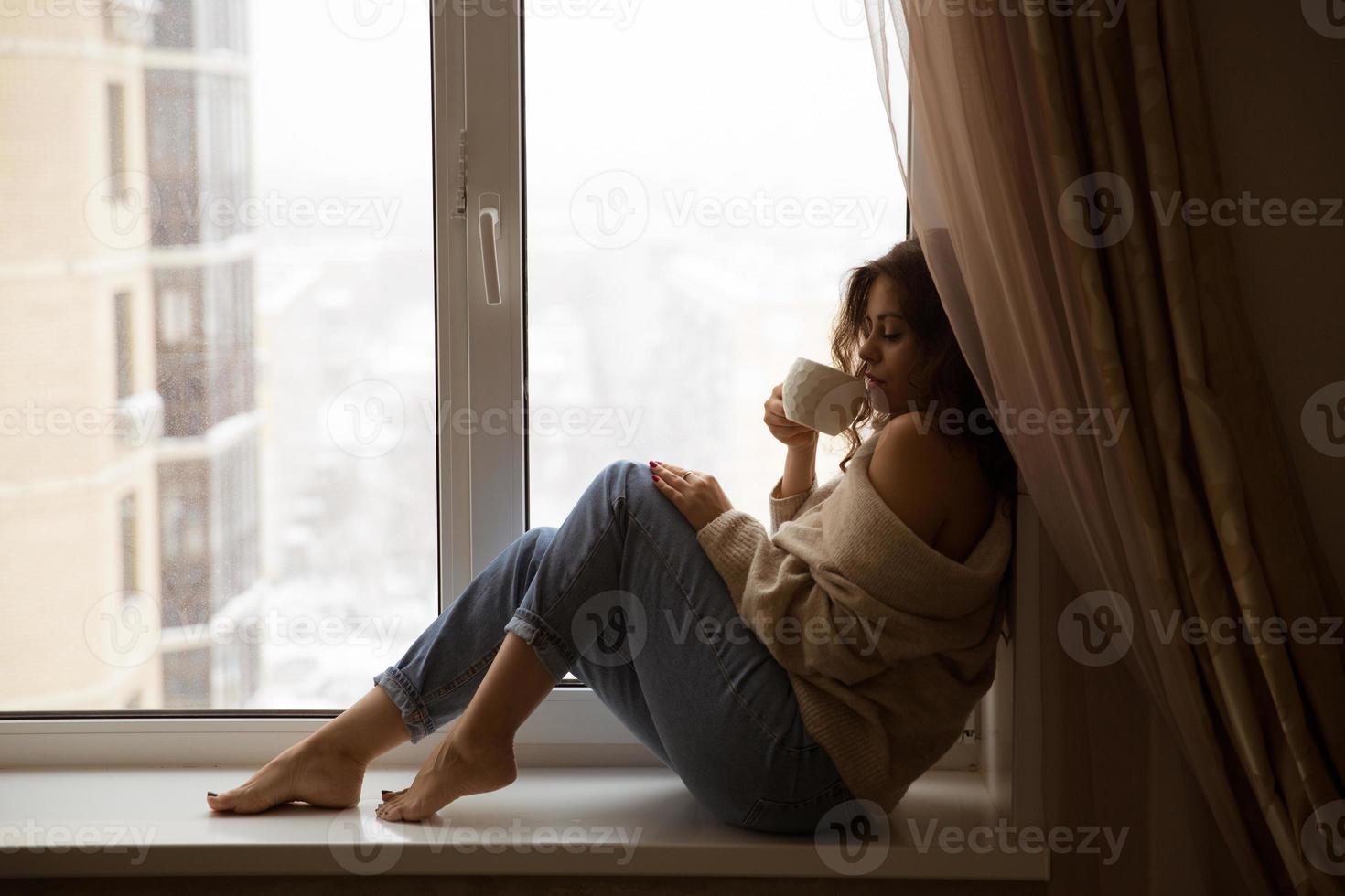 donna alla finestra che beve caffè foto