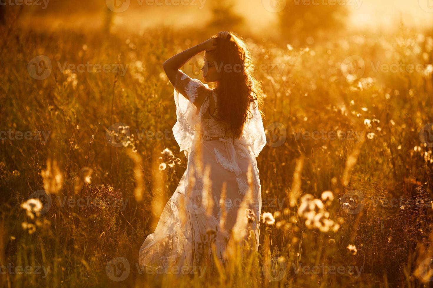 la ragazza sta in un campo al tramonto foto