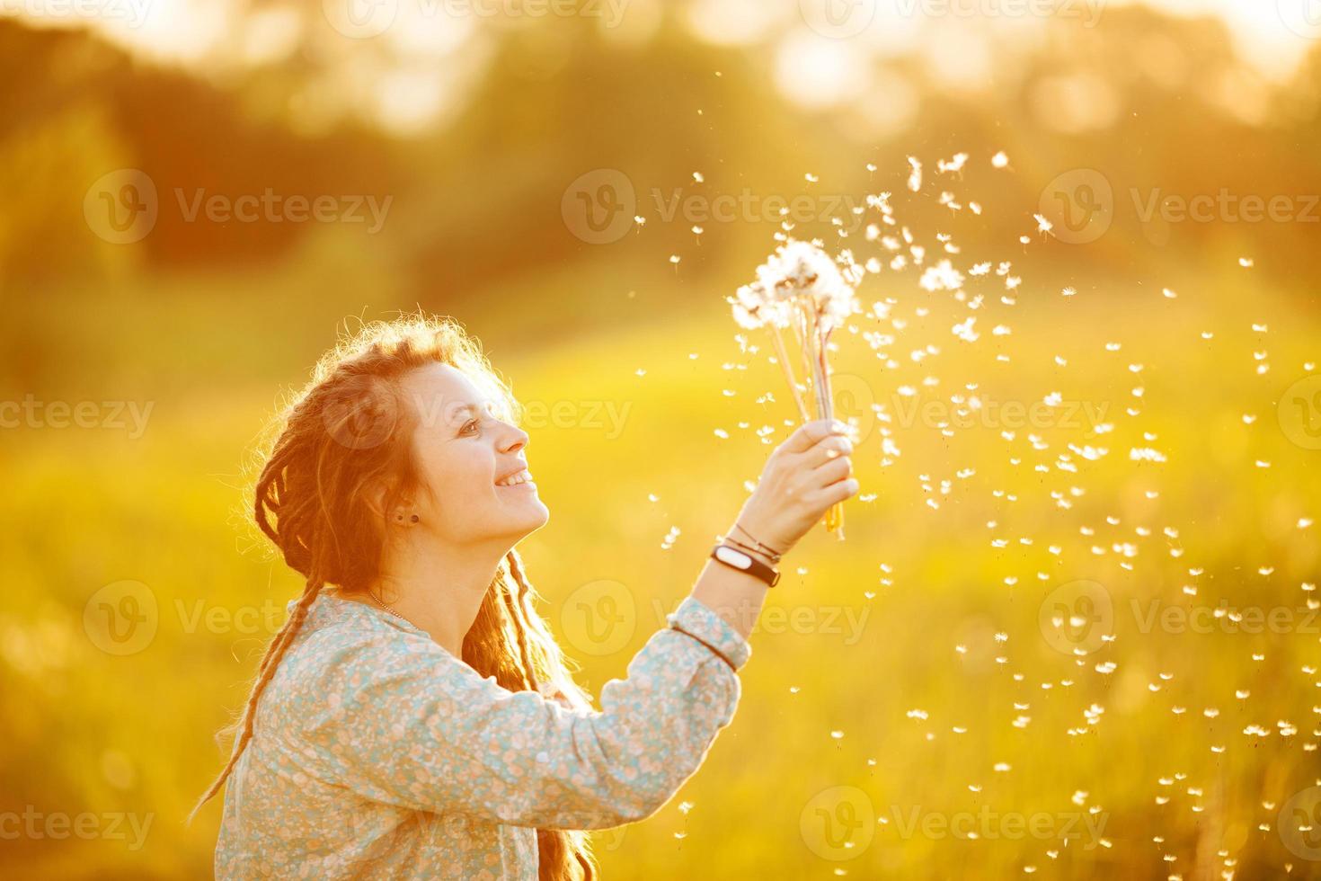 la ragazza guarda i denti di leone che volano foto