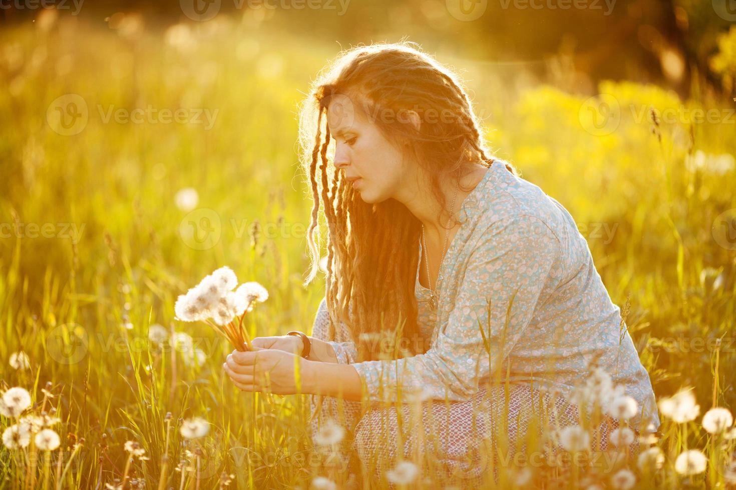 ragazza con i dreadlocks che strappa i denti di leone foto