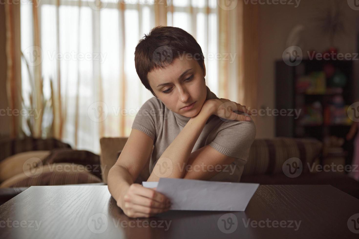 bella donna che legge una lettera al tavolo foto