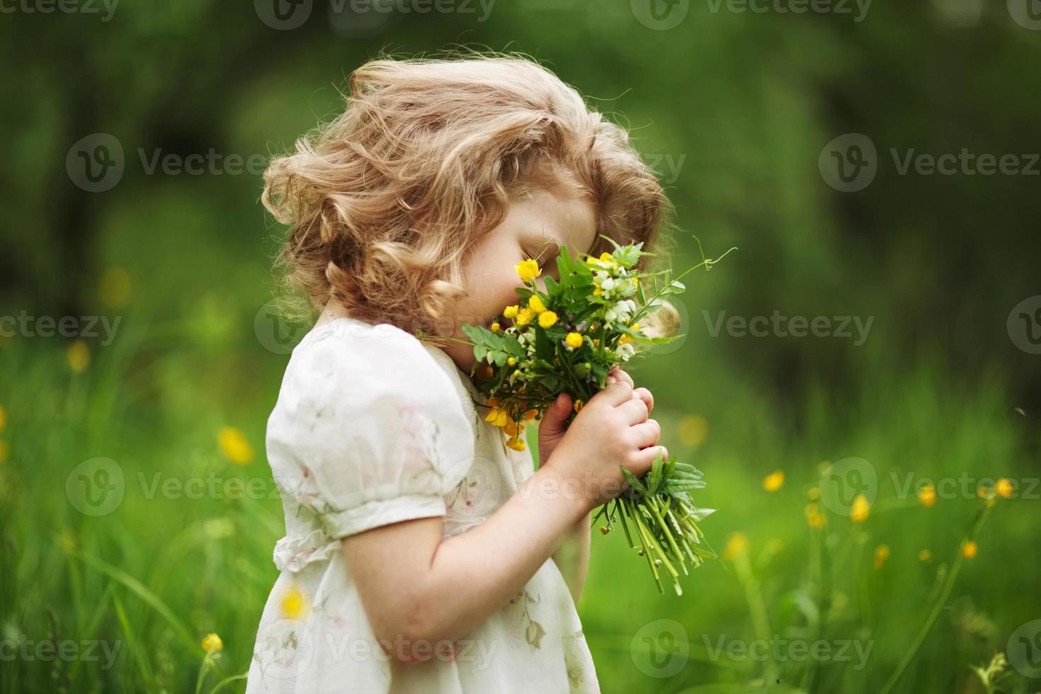 bambina che odora un mazzo di fiori foto