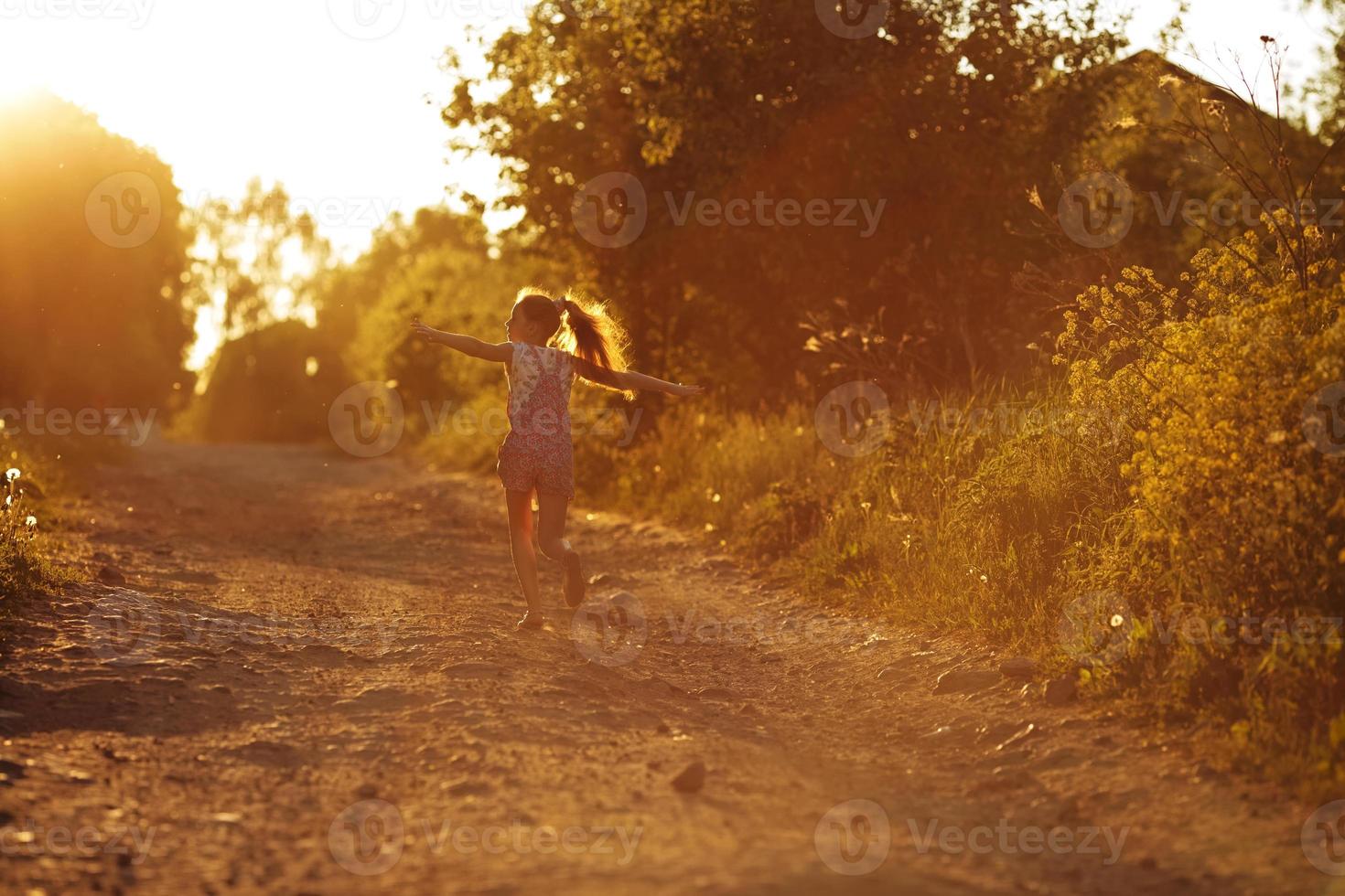 bambina felice che corre lungo una strada di campagna foto