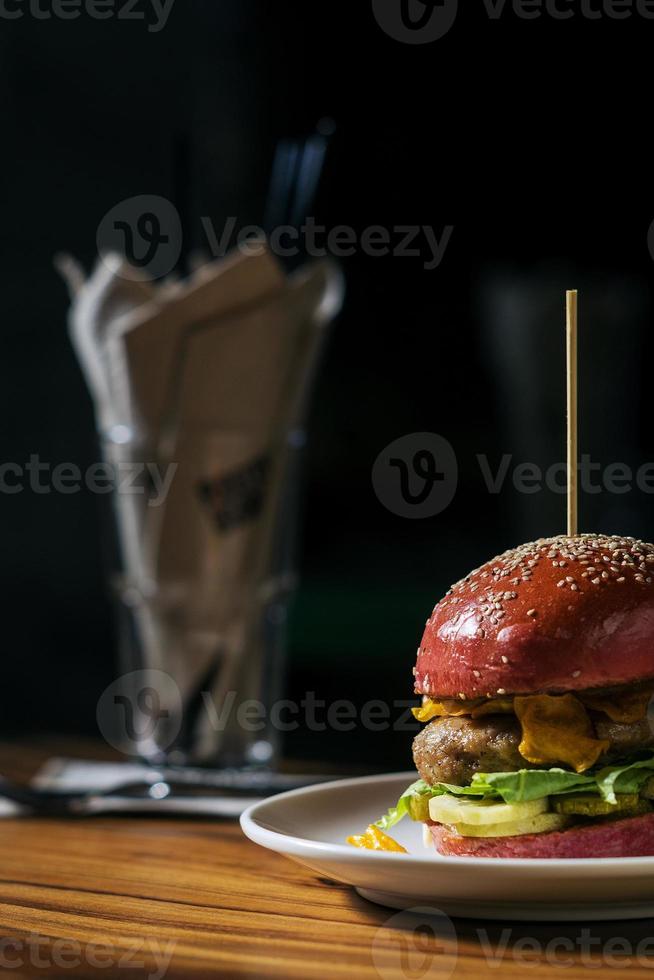 hamburger di pollo alla moda gourmet moderno in panino alla barbabietola foto