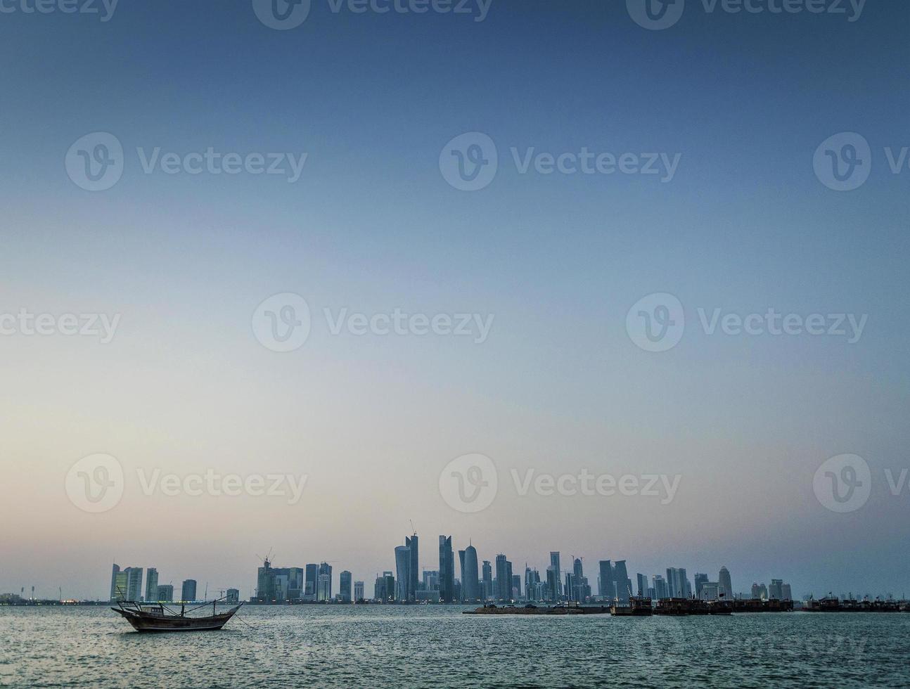 grattacieli della città di doha vista sullo skyline urbano e barca dhow in qatar foto