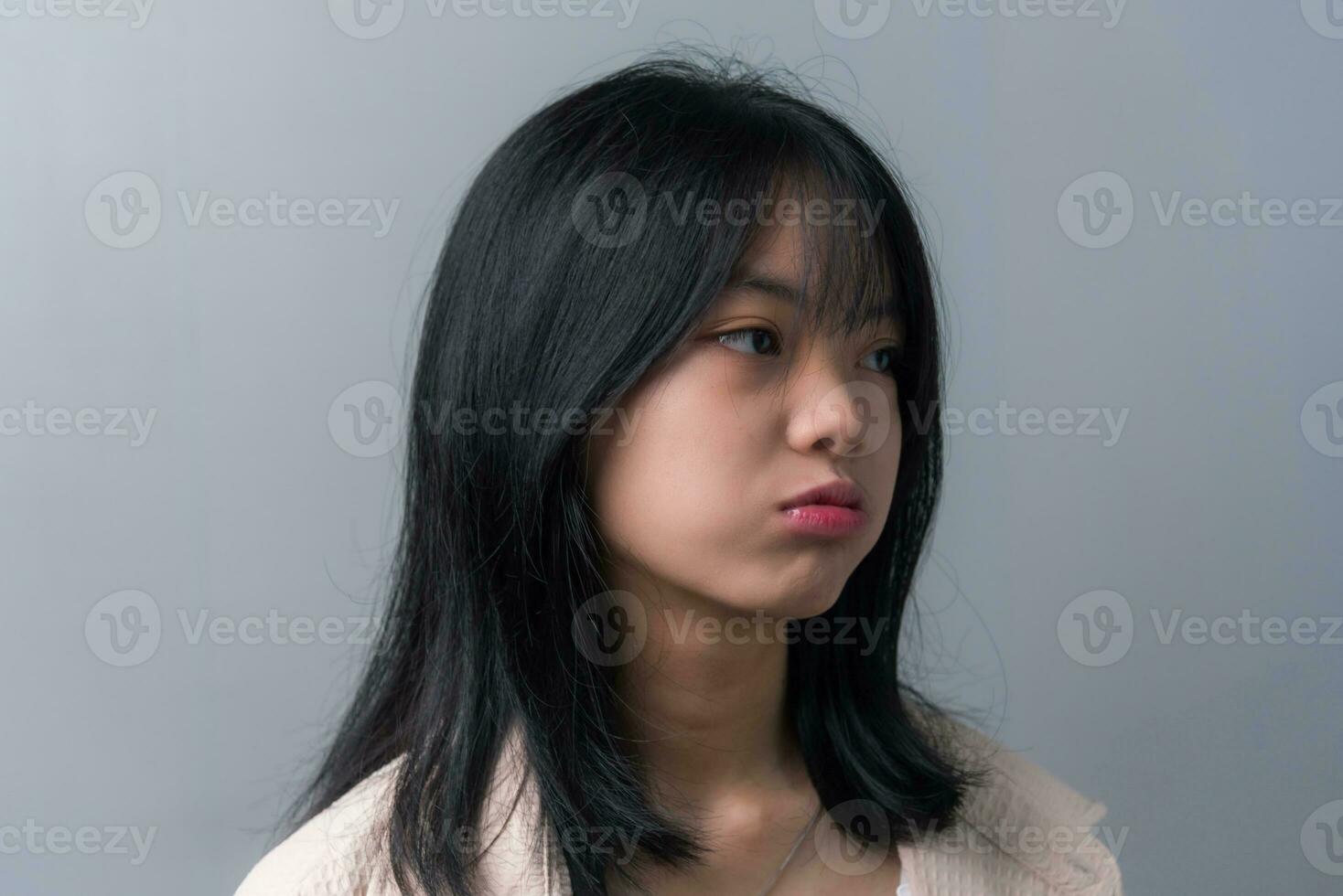 giovane bellissimo asiatico adolescenziale ragazza mostrando un' triste, deluso espressione su sfondo. foto