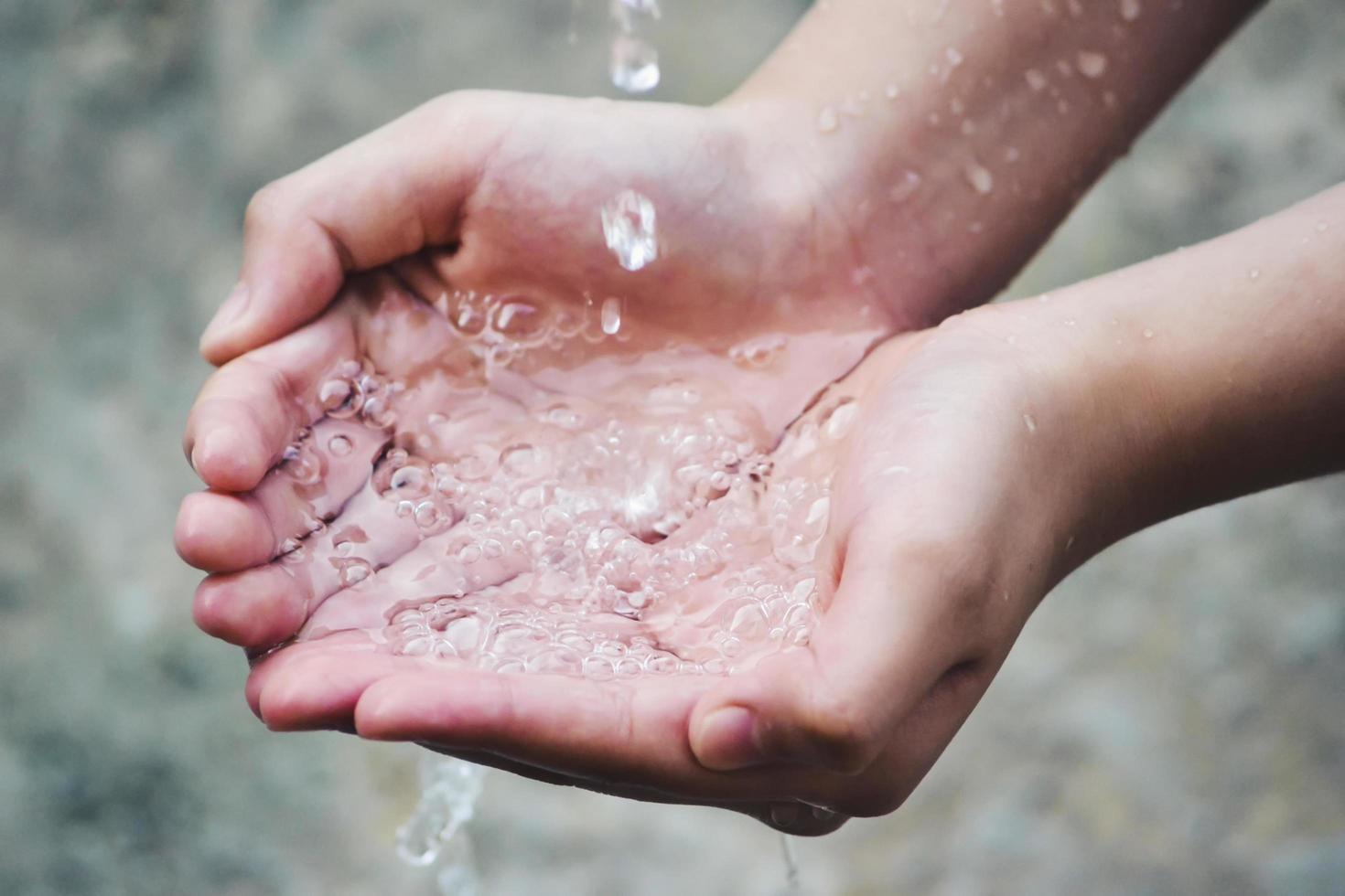 la mano cattura le gocce d'acqua che escono dal rubinetto foto