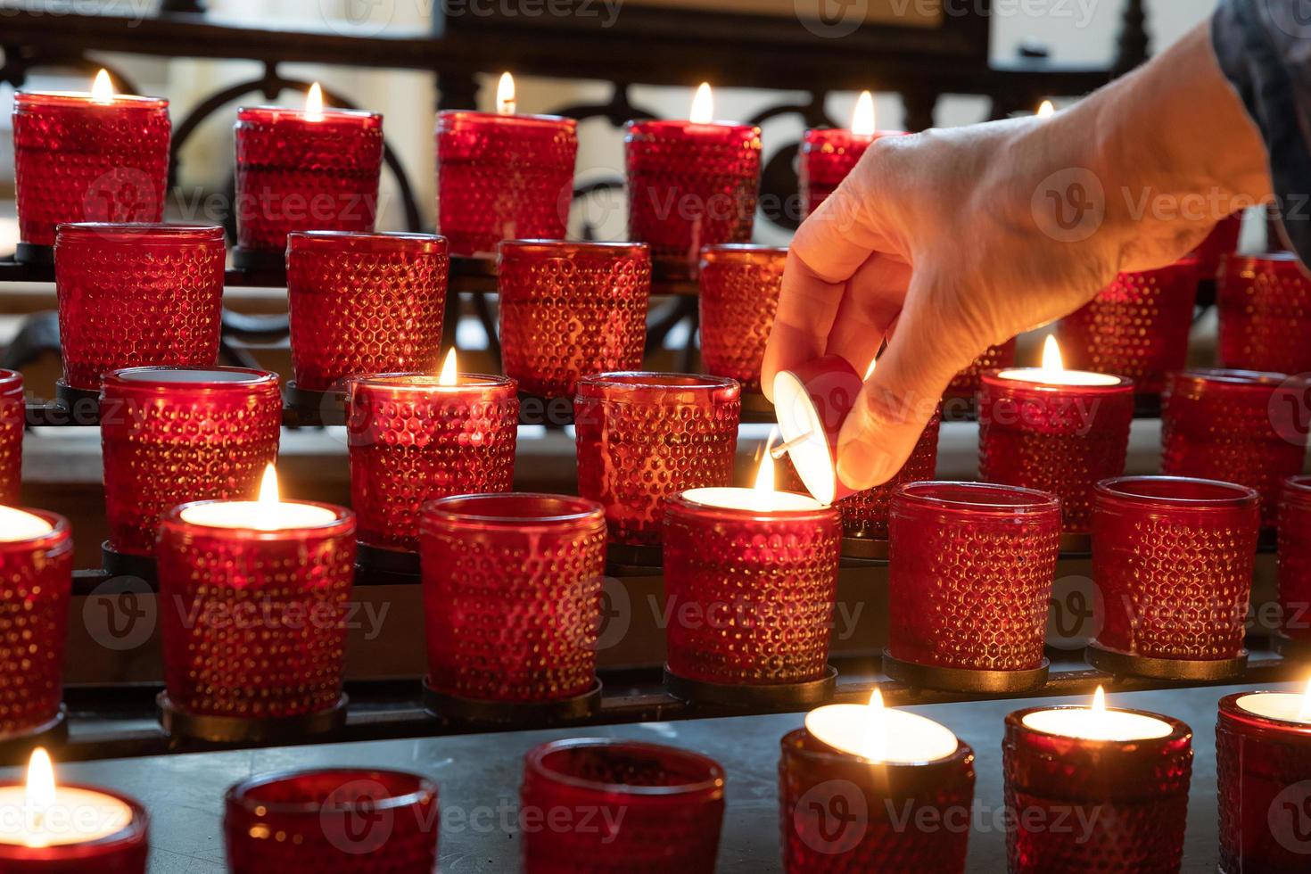 accendere una candela sacrificale rossa in una chiesa cristiana foto