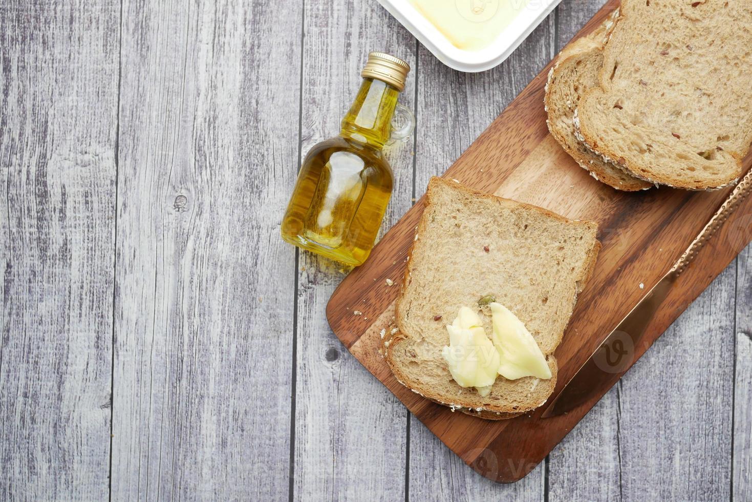 fetta di burro e pane integrale sul tagliere foto