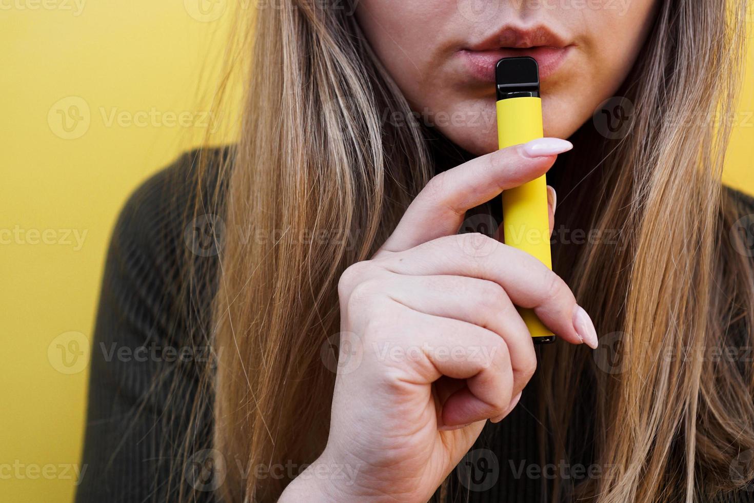 una ragazza fuma sigaretta elettronica usa e getta foto