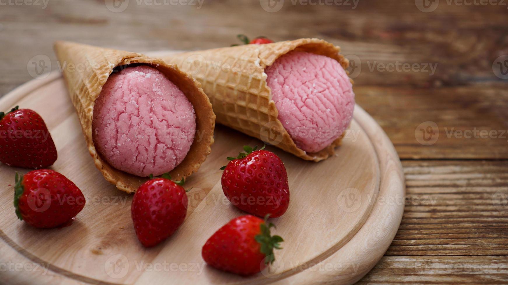 gelato alla fragola in un cono di cialda. bacche rosse e palline di gelato foto