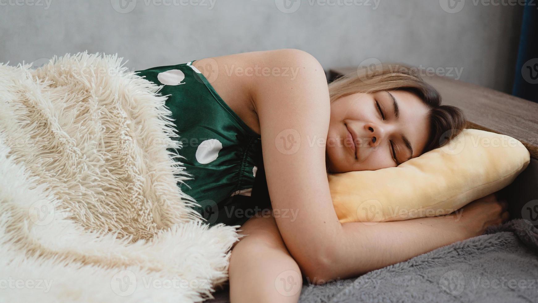 bella ragazza in una camicia da notte verde dorme su un cuscino giallo foto