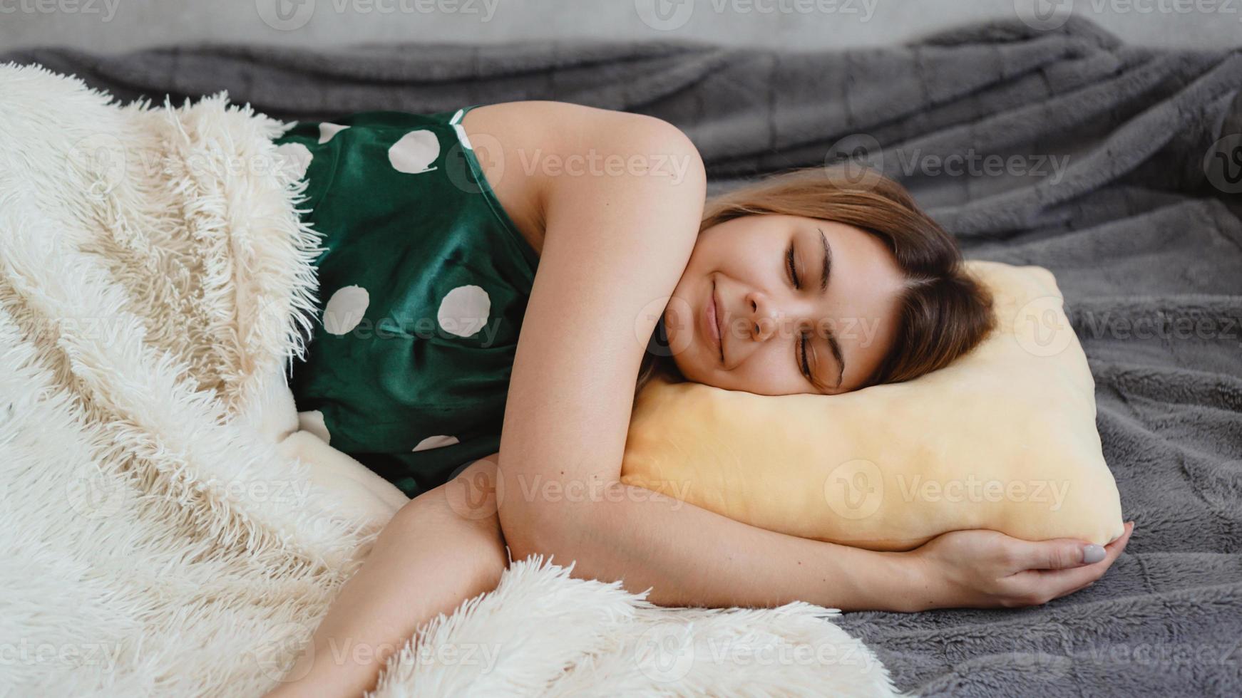 bella ragazza in una camicia da notte verde dorme su un cuscino giallo foto