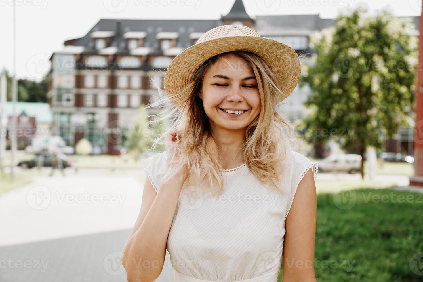 una bella bionda cammina per una città. donna in abito bianco foto