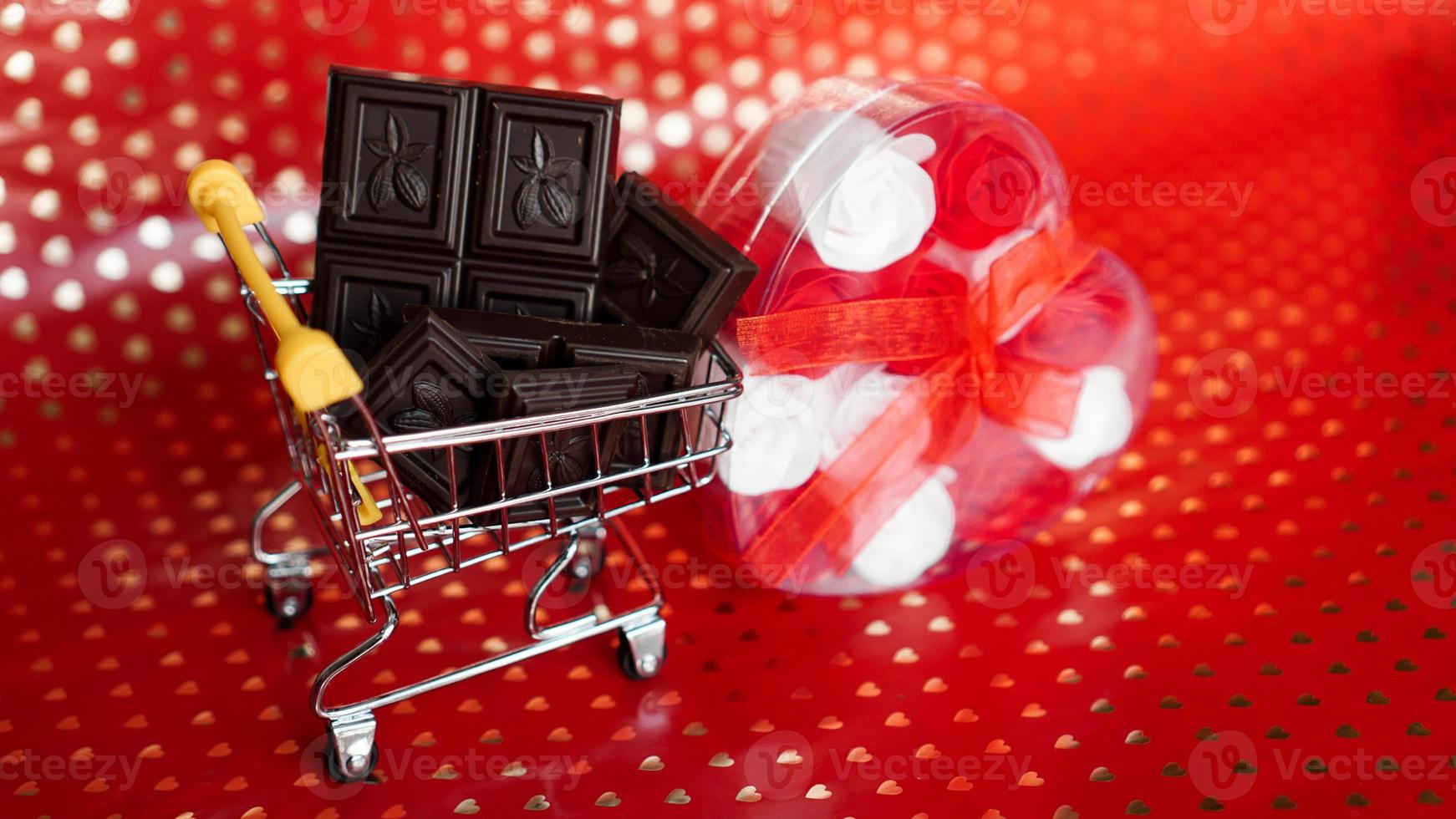 cioccolato nel carrello della spesa e rose su rosso foto