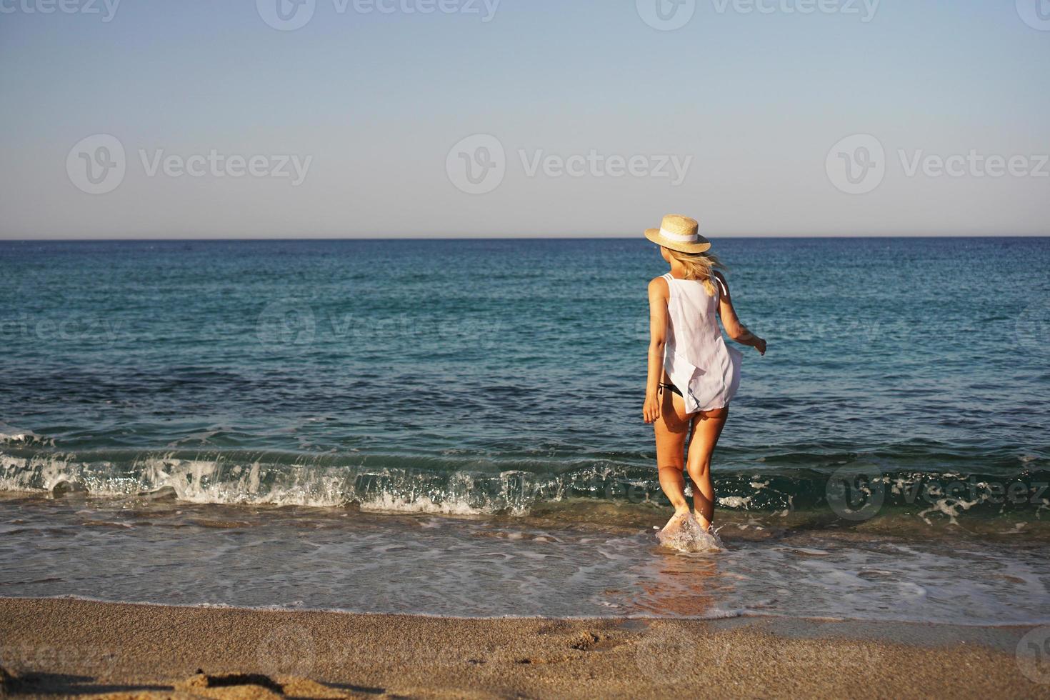 ragazza cammina sulla spiaggia. bella donna bionda foto