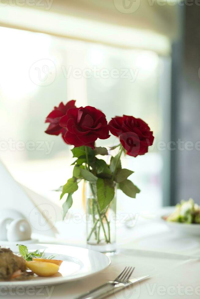 tavolo ambientazione per romantico cena con rosso Rose nel vaso su tavolo foto