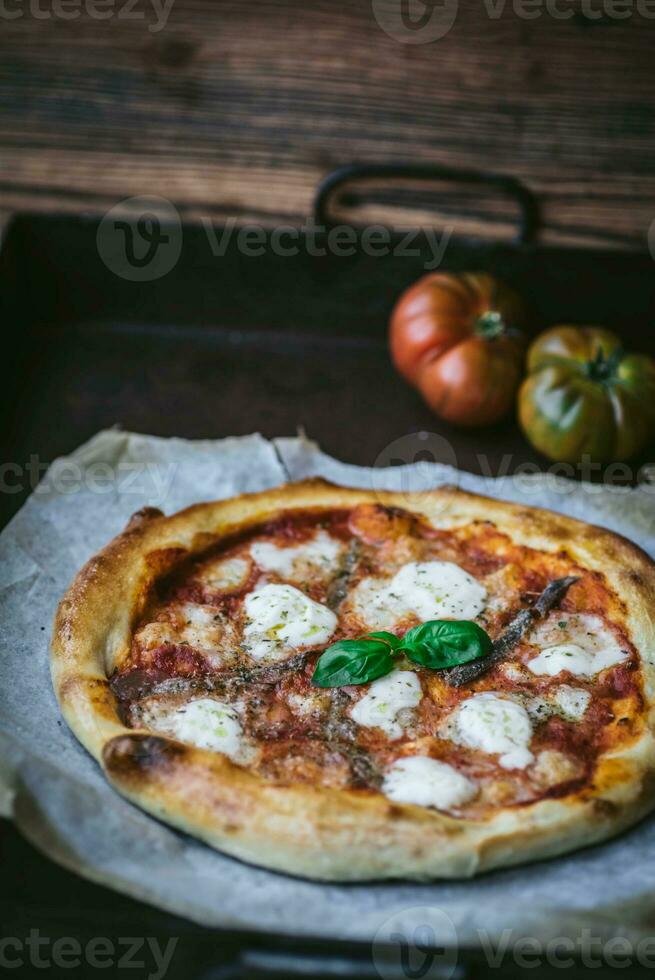 Pizza con Mozzarella, pomodoro e basilico su di legno sfondo foto