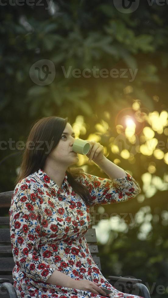 giovane donna in un abito floreale che beve una tazza di caffè foto