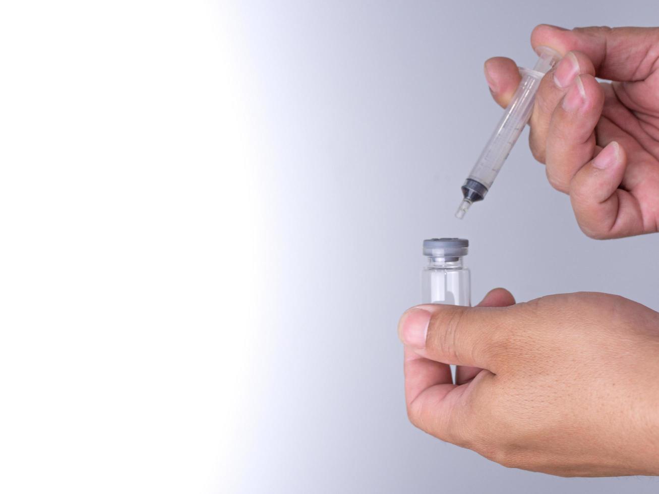 la mano di un uomo tiene una bottiglia di vaccino e una fionda per l'iniezione. foto